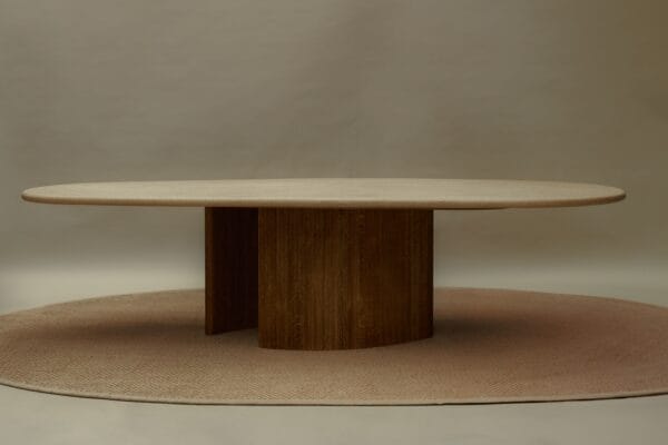 Straight-on view of the Caprice dining table, placed on a round beige rug under soft studio lighting.