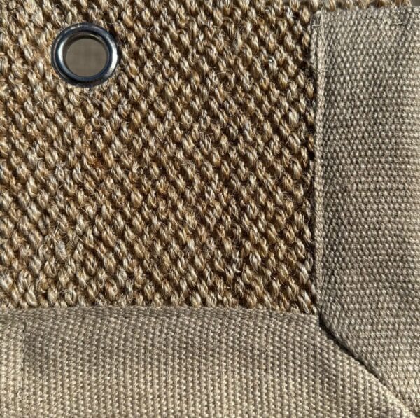 Close-up of Sisal 01 in color 13, showing a tightly woven natural fiber texture with a fabric border and a metal eyelet.