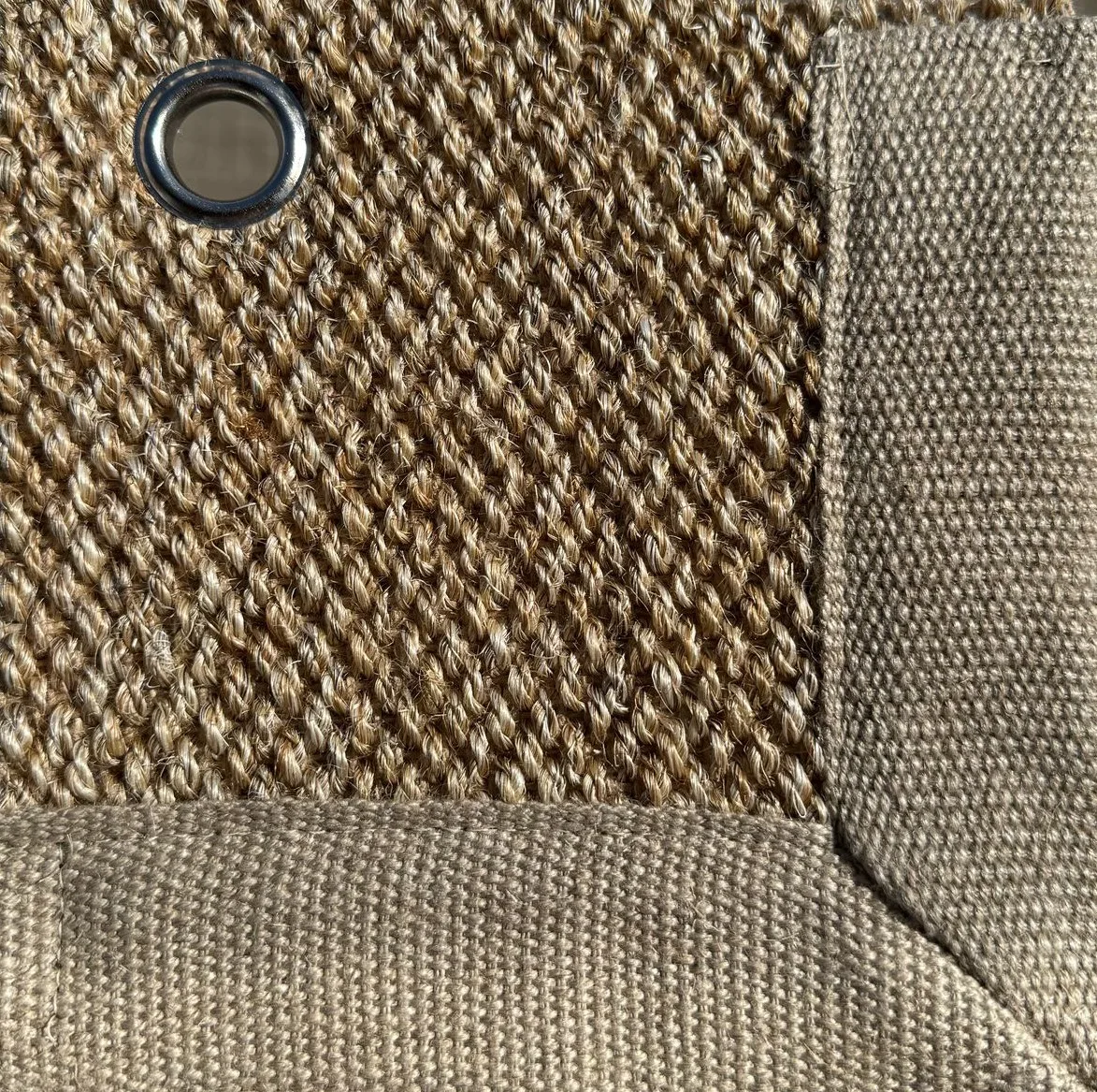 Close-up of Sisal 01 in color 13, showing a tightly woven natural fiber texture with a fabric border and a metal eyelet.