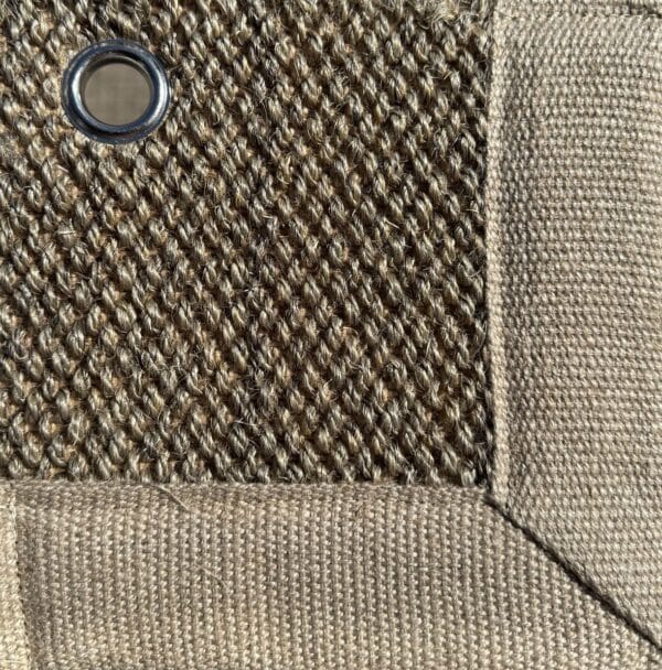 Close-up of Sisal 01 in color 22, showing a tightly woven natural fiber texture with a fabric border and a metal eyelet.