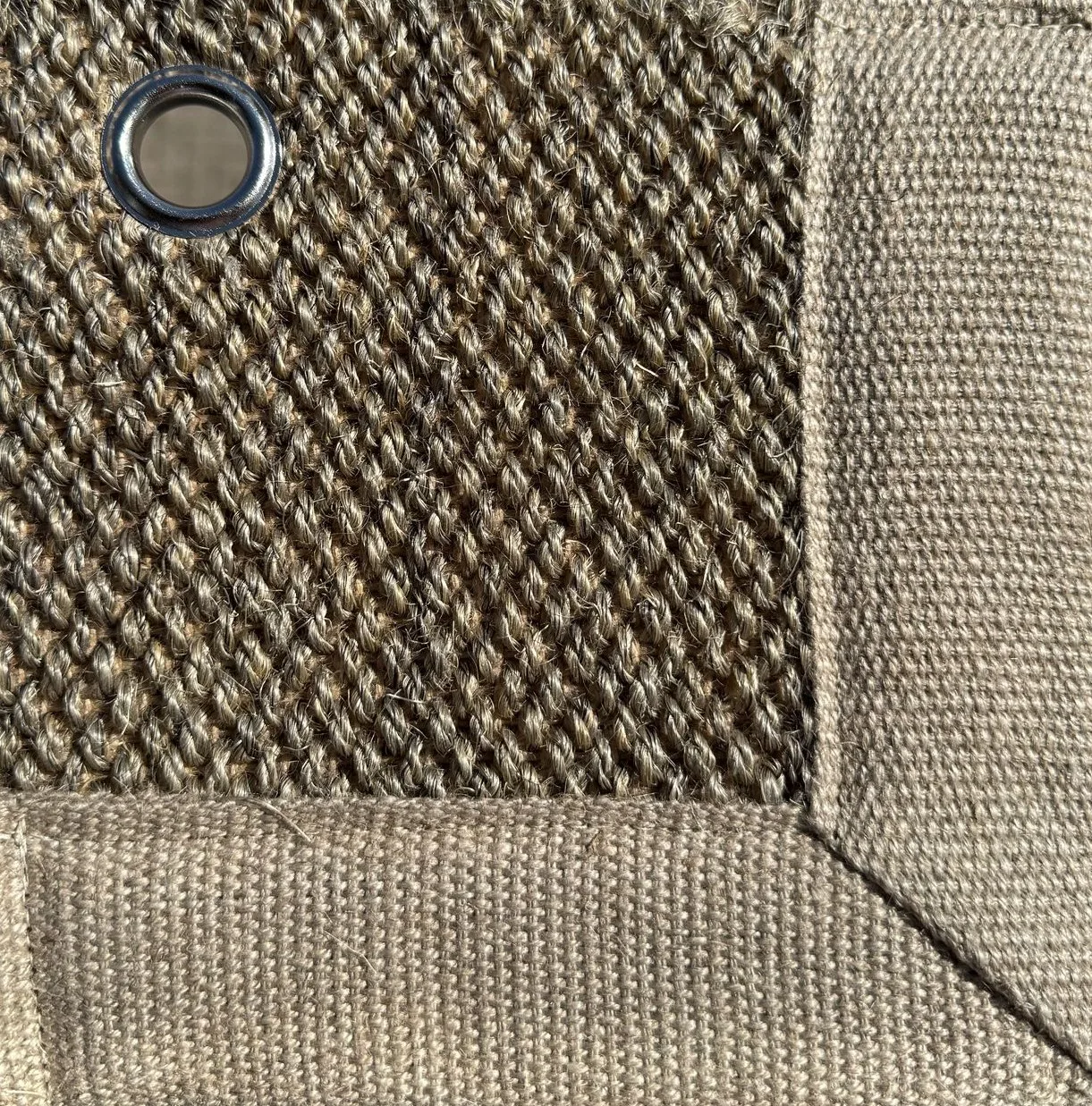 Close-up of Sisal 01 in color 22, showing a tightly woven natural fiber texture with a fabric border and a metal eyelet.