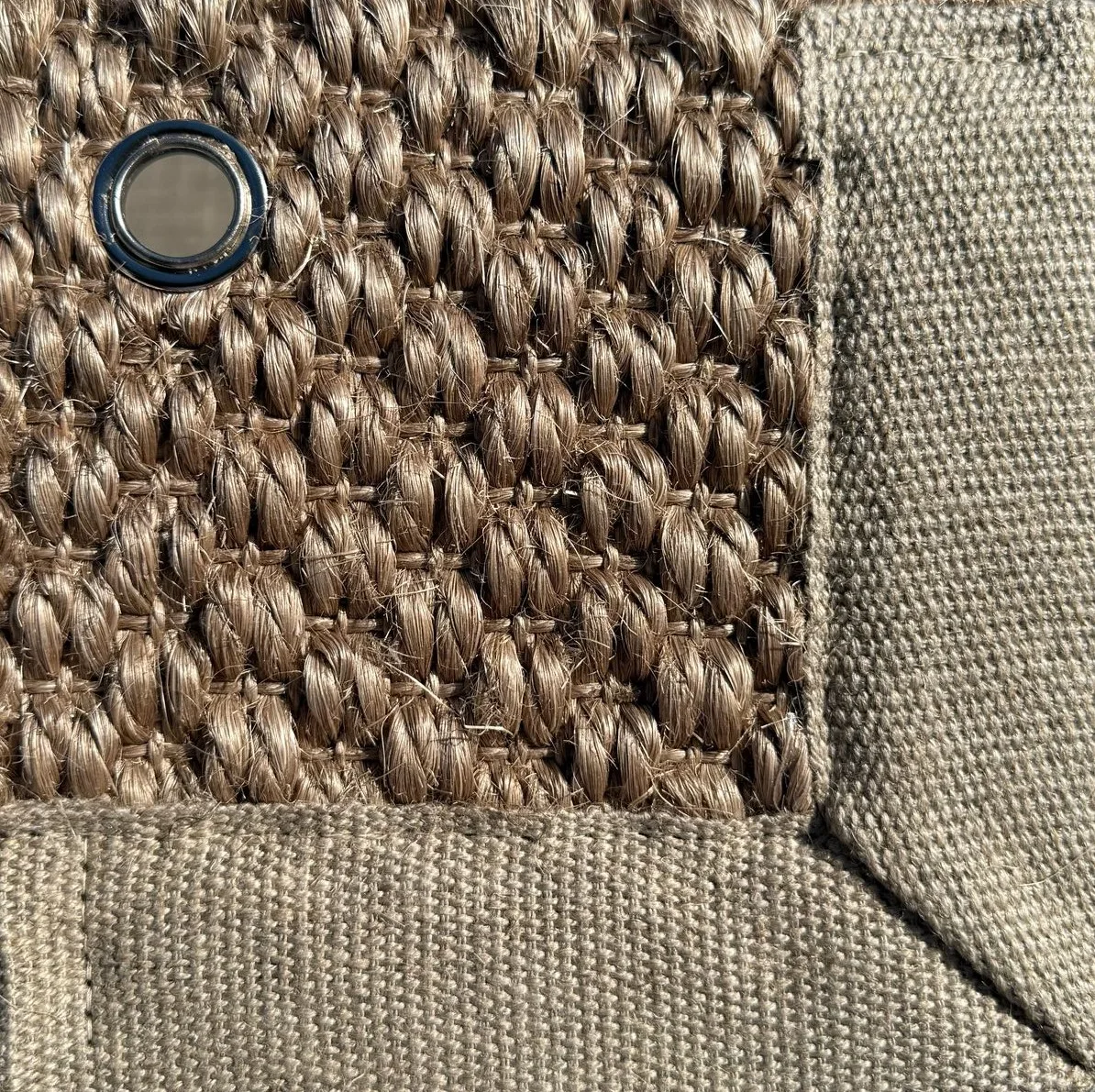 Close-up of Sisal 03 in color 21 showing a tightly woven natural fiber texture with a fabric border and a metal eyelet.