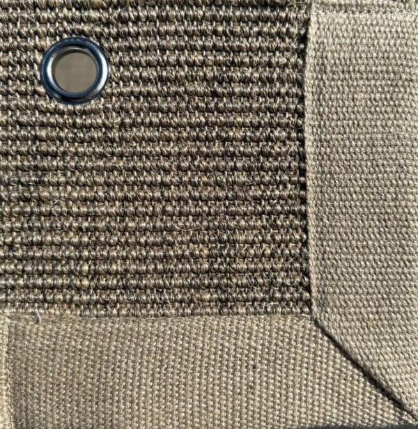 Close-up of Sisal 05 in color 17, showing a tightly woven natural fiber texture with a fabric border and a metal eyelet.