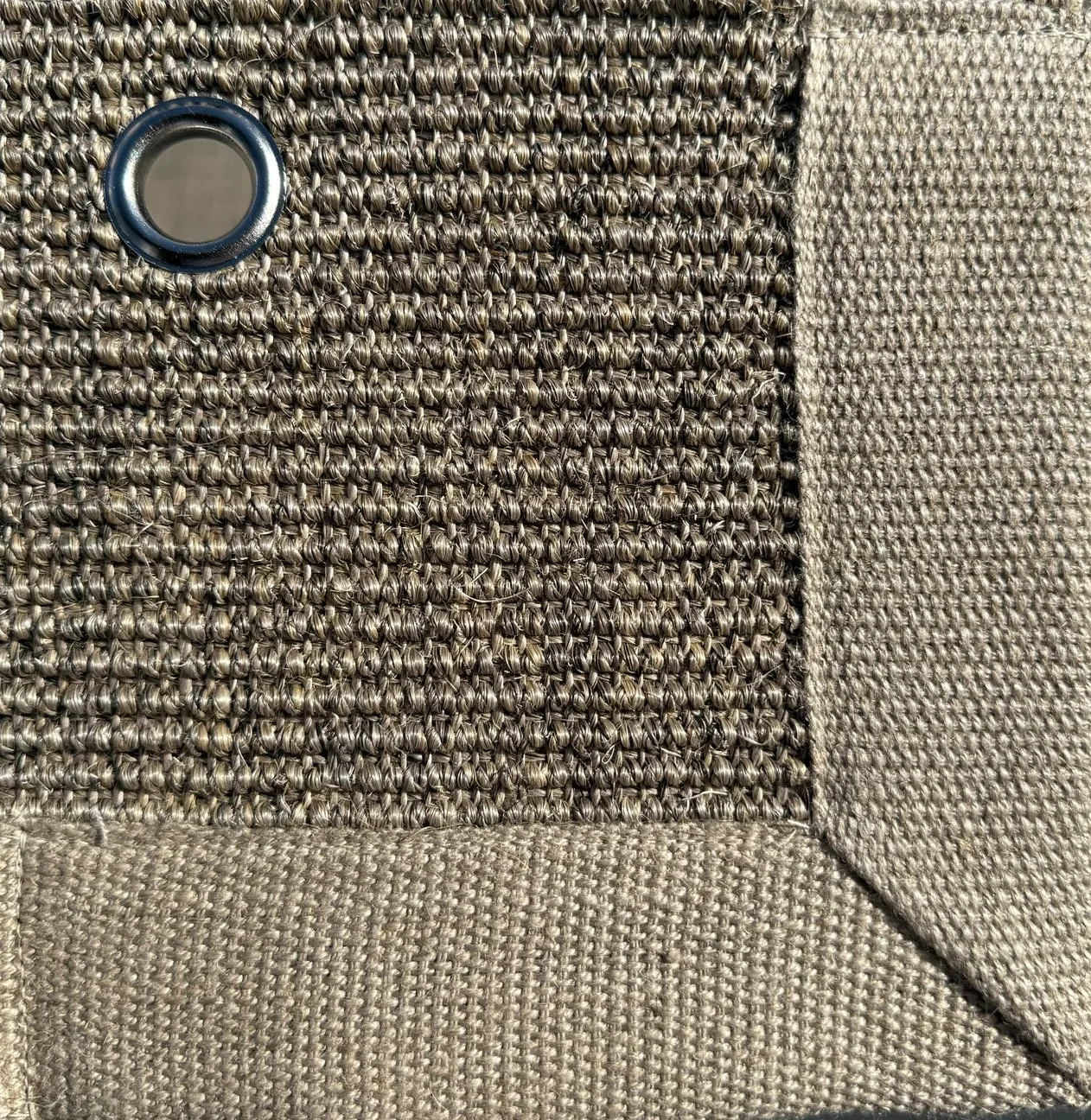 Close-up of Sisal 05 in color 17, showing a tightly woven natural fiber texture with a fabric border and a metal eyelet.