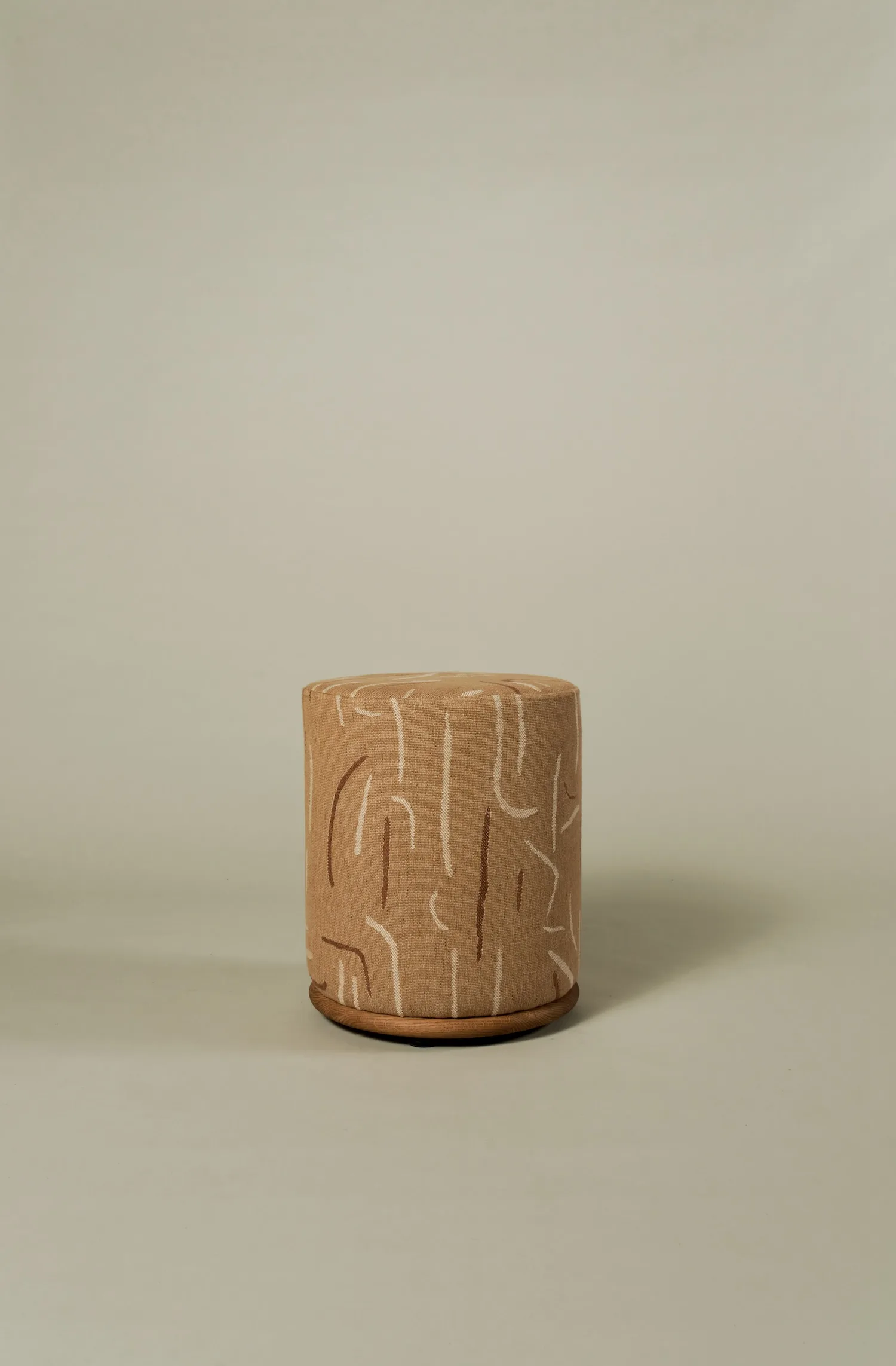 Standalone Ackley pouf featuring a playful woodgrain-inspired embroidered pattern.