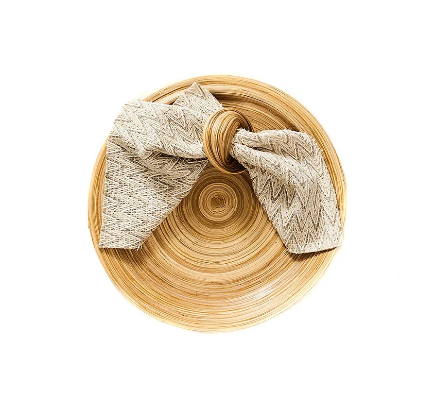 Top view of a bamboo napkin ring holding a neatly tied fabric napkin in a bow shape.