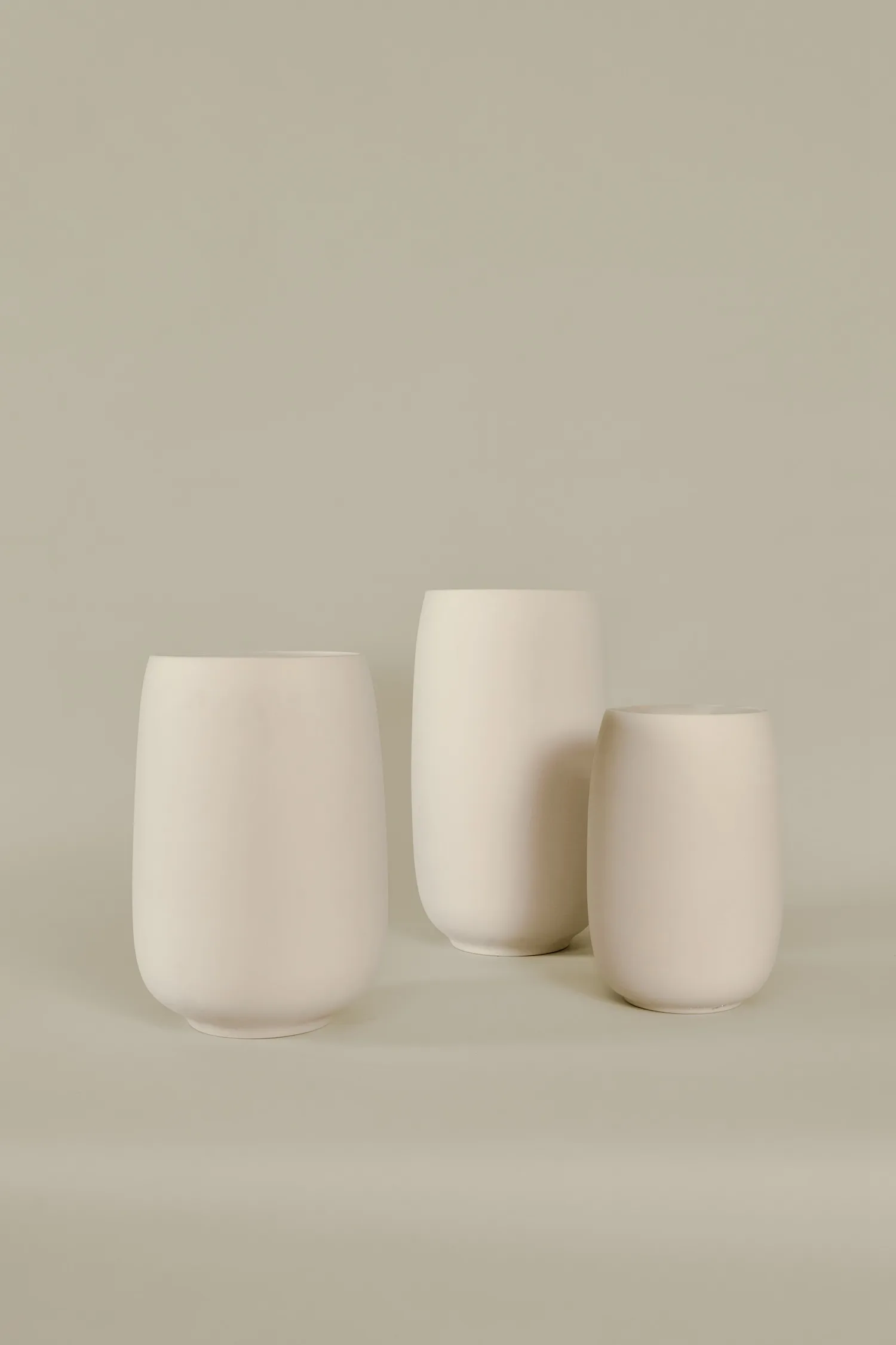 Set of three minimalist off-white Bola vases in various heights on a neutral background.