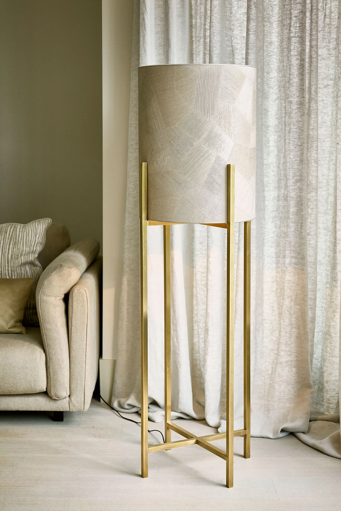 Cato floor lamp with a patchwork-textured cylindrical shade and a gold metal frame placed in a soft-toned interior.