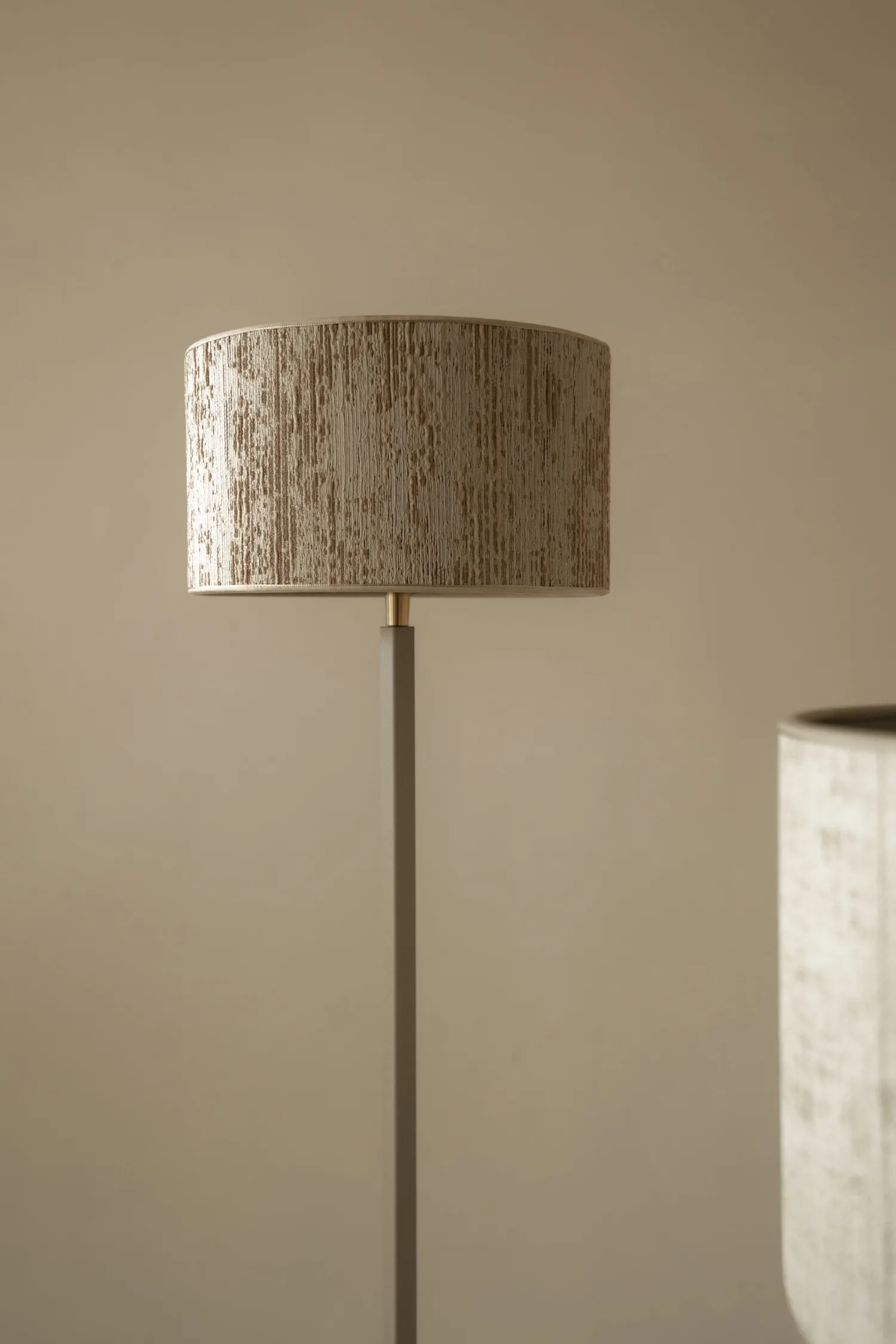 Close-up of Duld floor lamp with cylindrical textured lampshade and minimal pole design.
