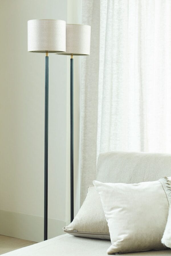 Pair of Duld floor lamps with hammered white shades next to a light-colored sofa.