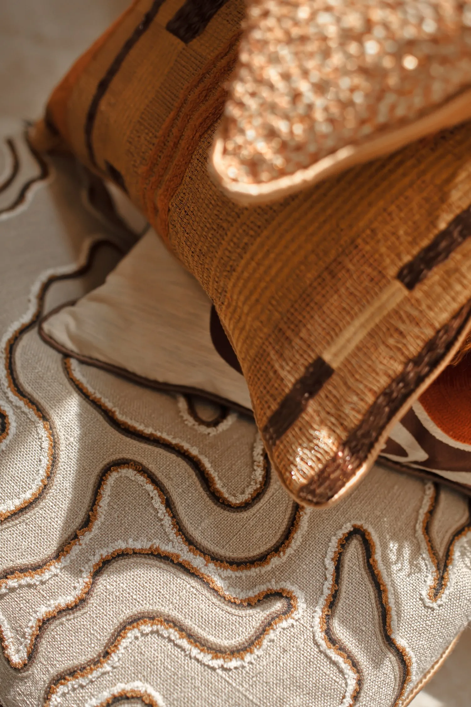 Close-up of cushions showcasing detailed embroidery and woven textures in warm, earthy colors.