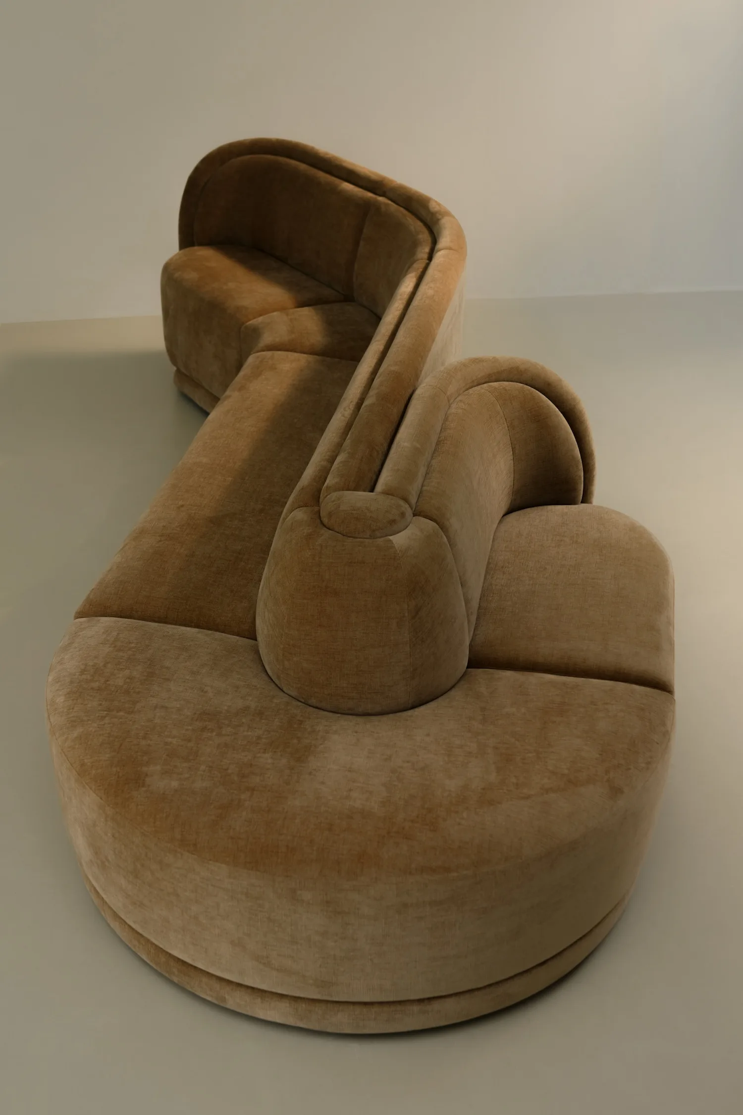 Top-down view of a sculptural, curved Georgie modular sofa in camel velvet, showcasing its organic shape and plush upholstery.