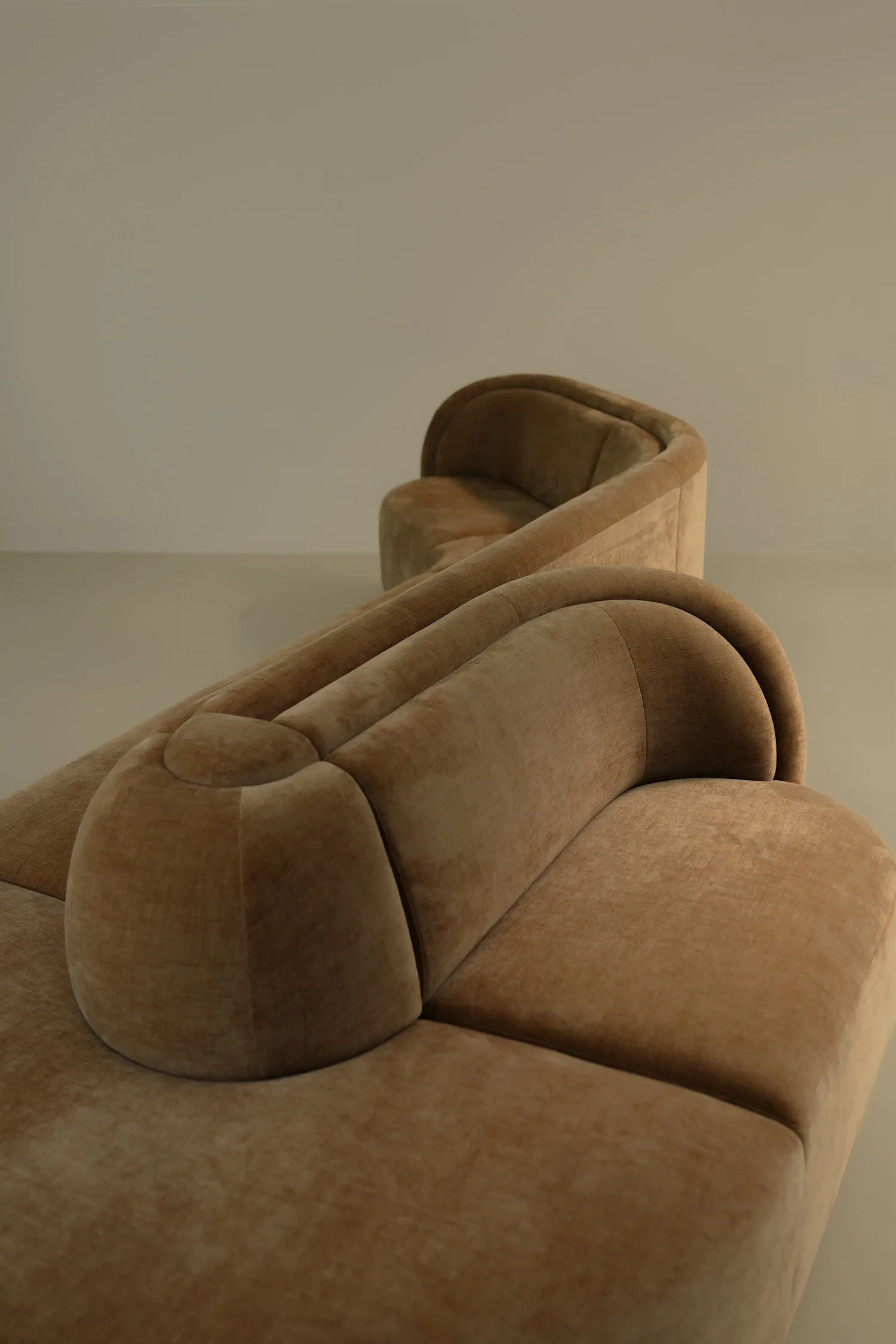 Close-up of the backrest detail of a curved camel-colored Georgie modular sofa, highlighting its rounded, sculptural design.