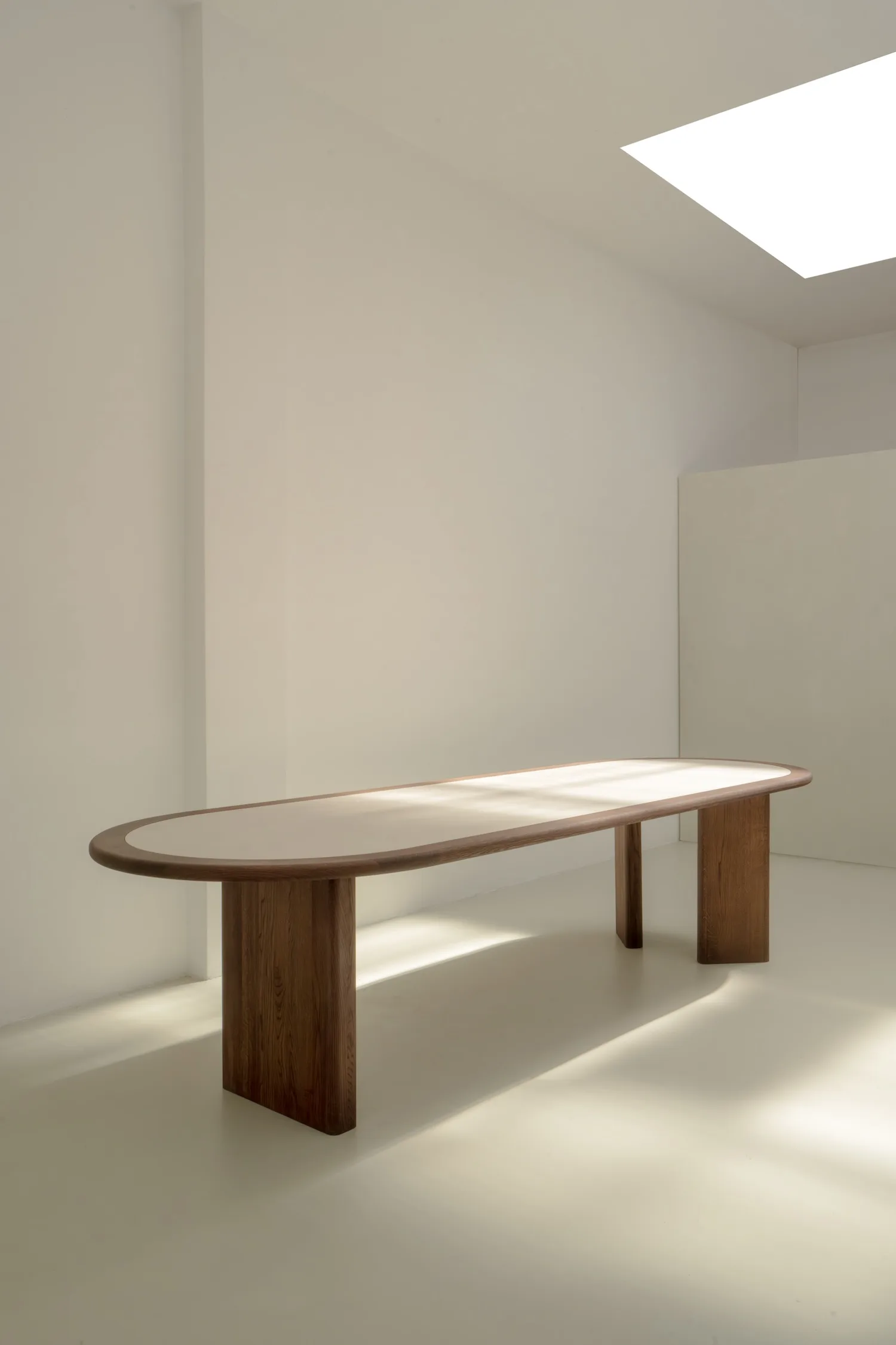 Side angle of the Hudson dining table showcasing its elongated oval form and wooden legs.