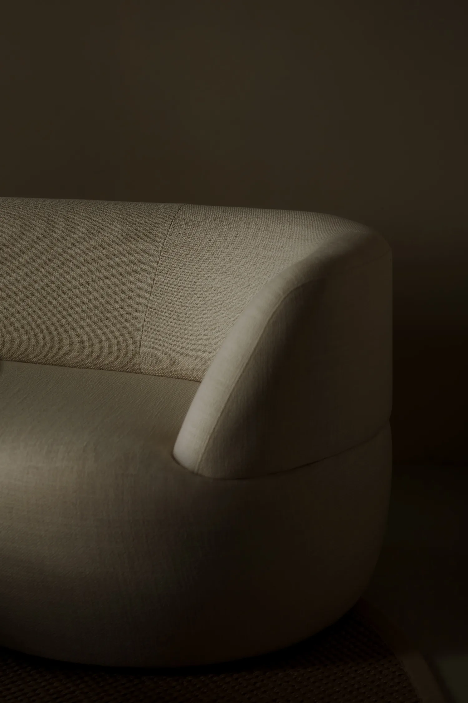 Close-up of the Jane sofa armrest, highlighting its textured fabric and rounded shape in soft lighting.