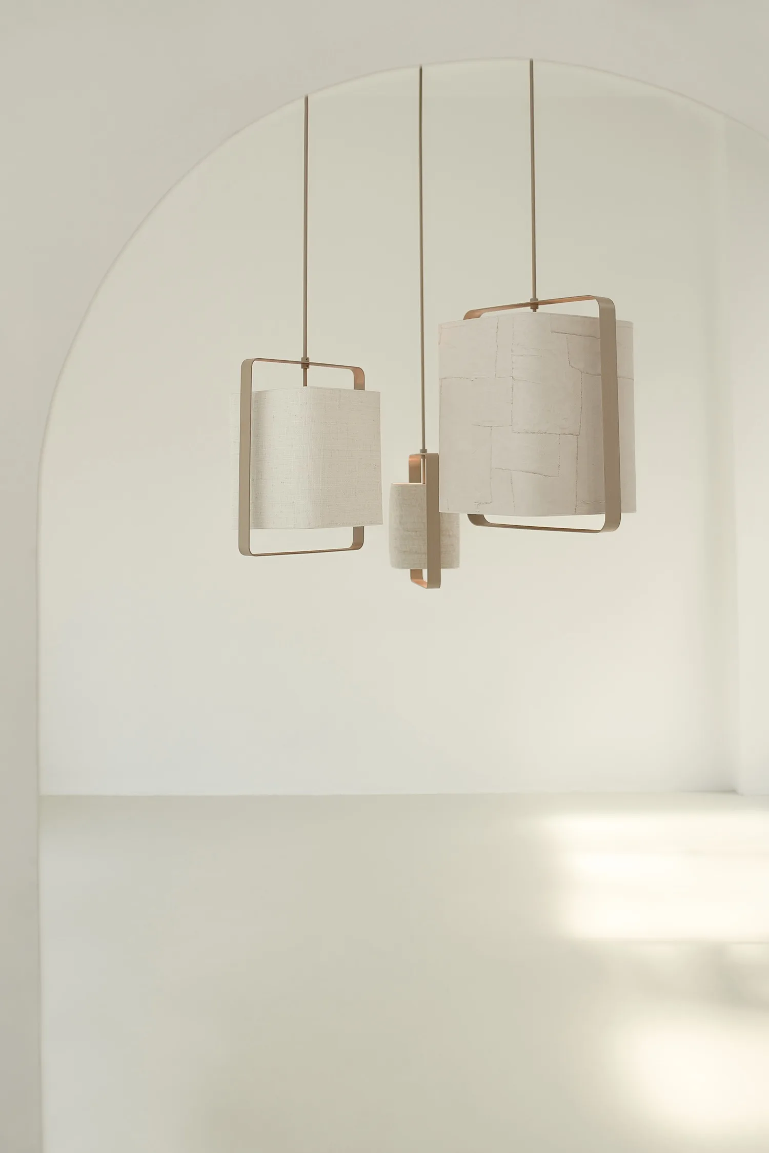 Set of three cylindrical Lora Ceiling Lights with minimalist frames hanging in an arched, all-white interior.