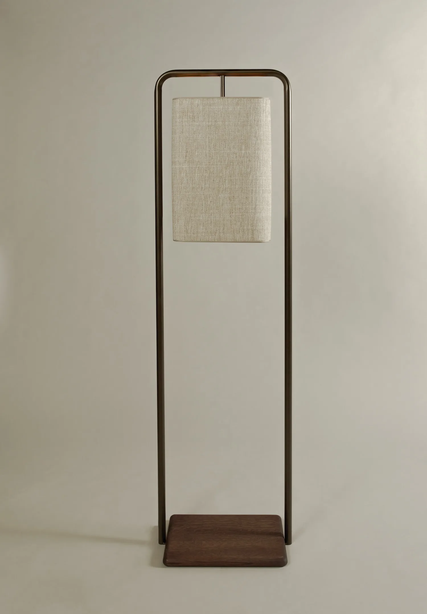 Single Lora floor lamp with a beige textile shade suspended within a bronze frame.