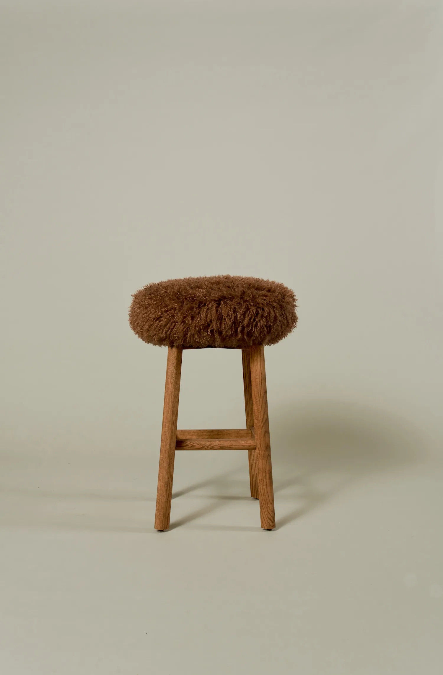 Margaux barstool with a fluffy brown shearling seat and oak legs.