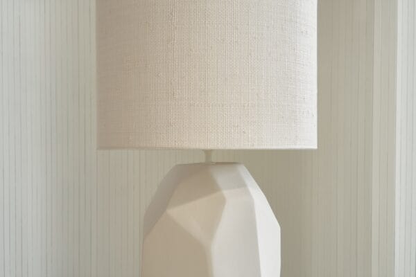 Detail of Mona lamp's faceted ceramic surface and light beige linen shade.