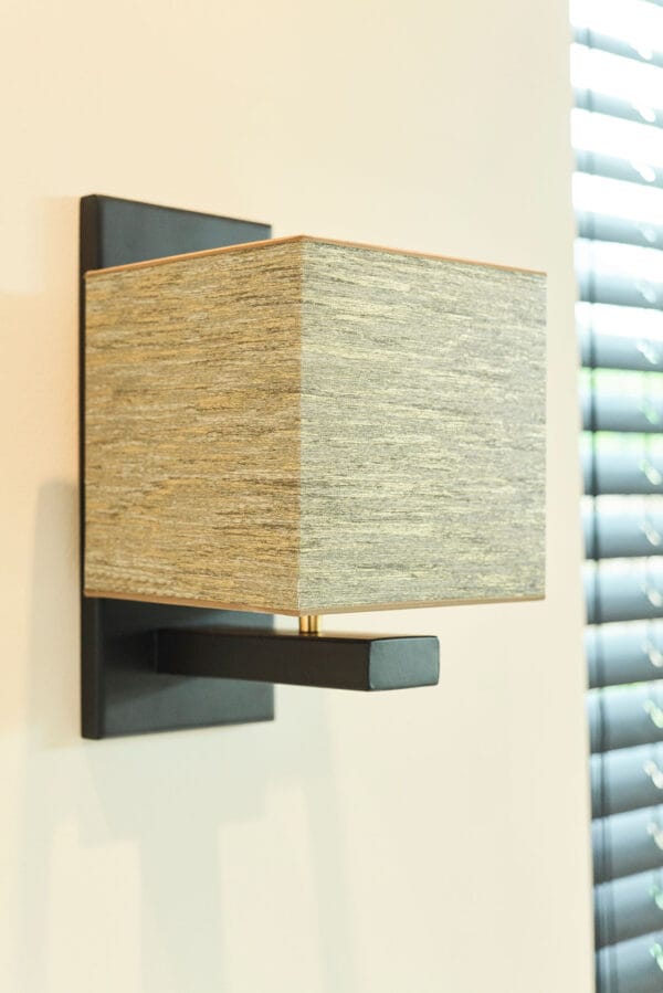Murillo wall light with a square beige fabric shade and black metal base.