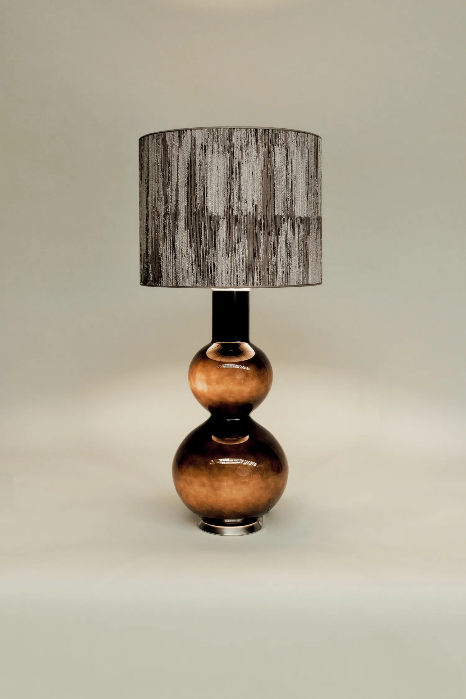Olivia table lamp with a glossy amber-toned double-gourd base and a textured dark patterned shade.
