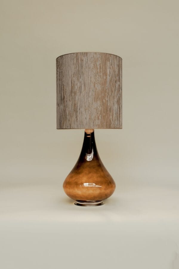 Studio shot of Paula lamp with a high-gloss brown glass base and vertically textured beige shade.