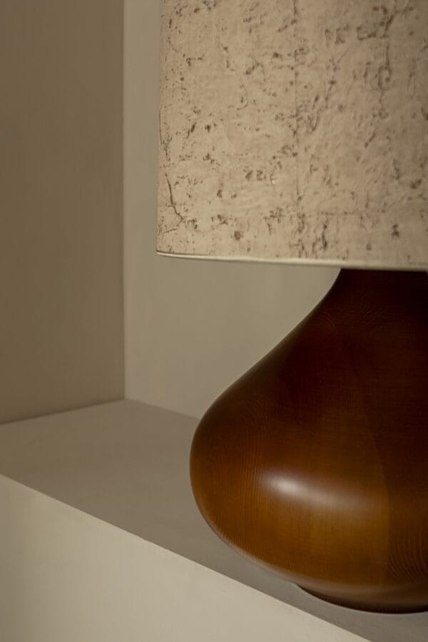 Detail view of Paula lamp’s amber-stained wooden base and pale cork-effect shade.