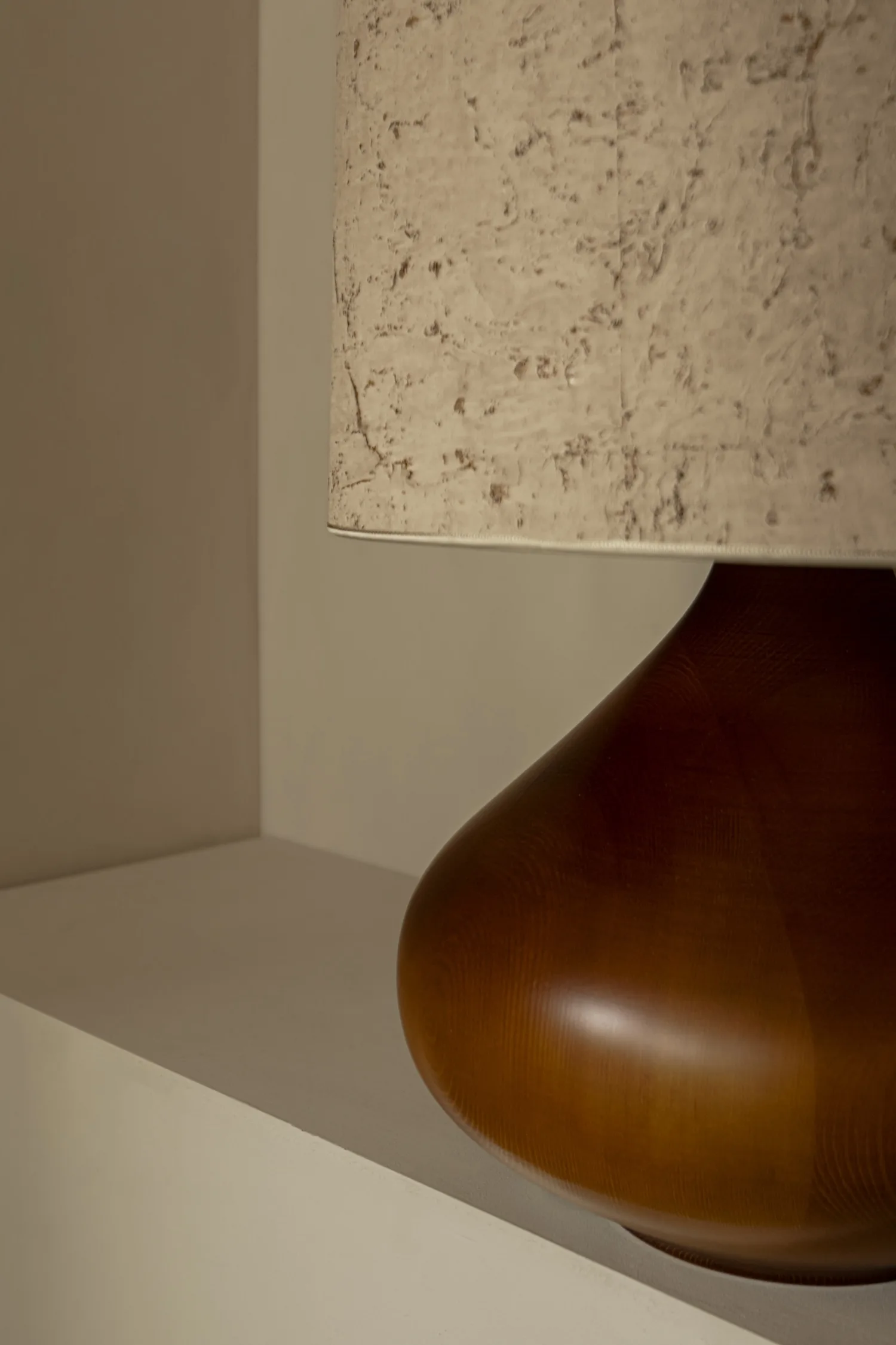 Detail view of Paula lamp’s amber-stained wooden base and pale cork-effect shade.