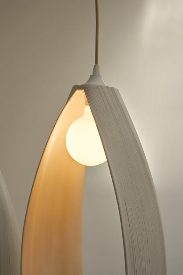 Close-up of a Petal ceiling light showing the curved wood structure and glowing bulb.