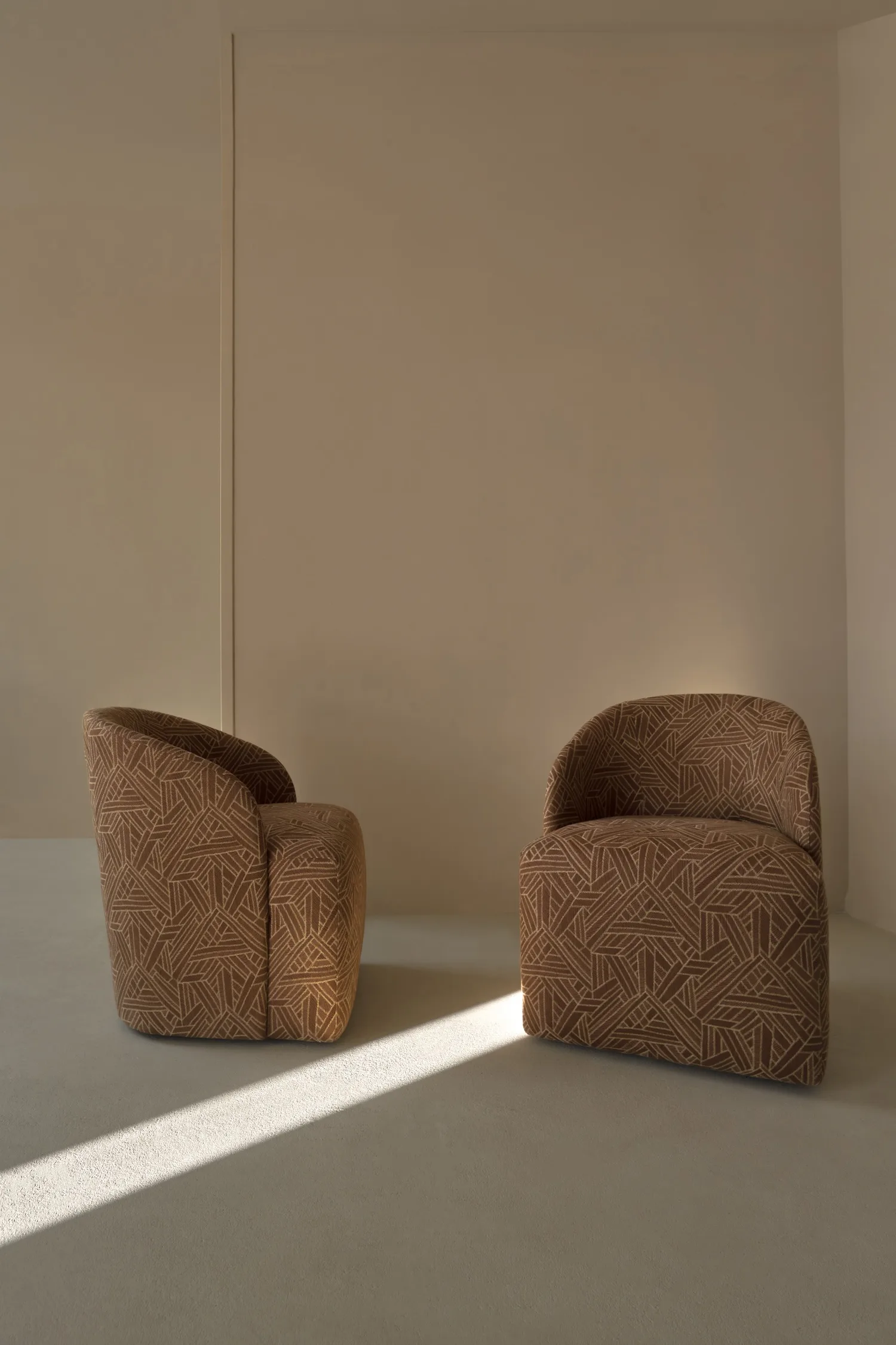 Two patterned Philia armchairs facing each other in a minimal beige interior.
