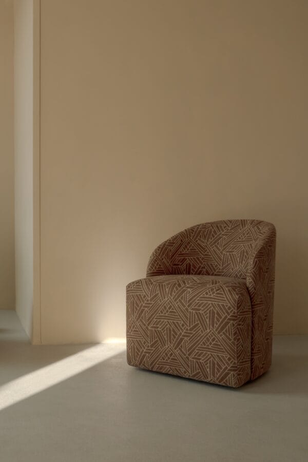 A single patterned Philia armchair placed against a neutral wall.