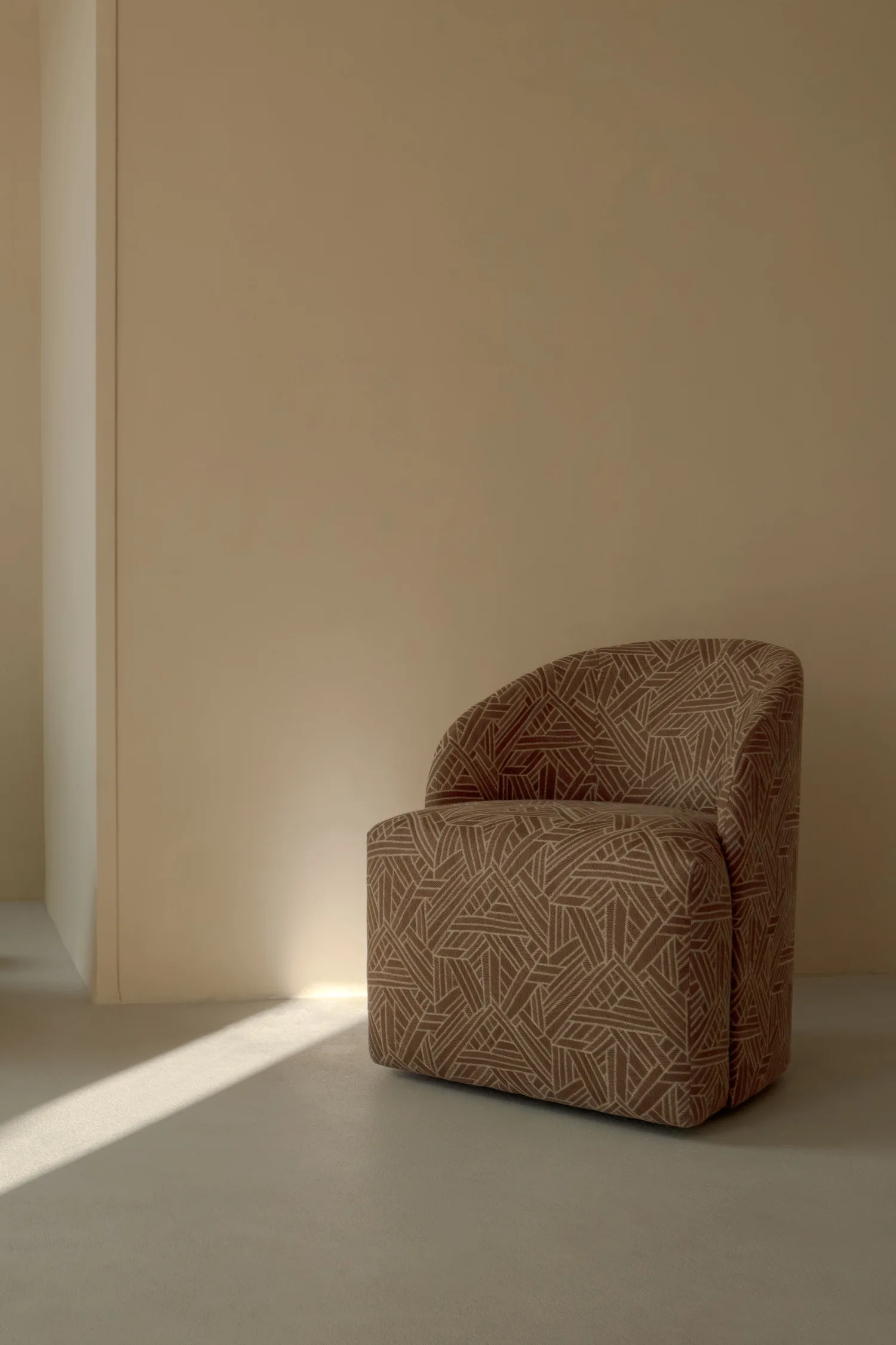 A single patterned Philia armchair placed against a neutral wall.