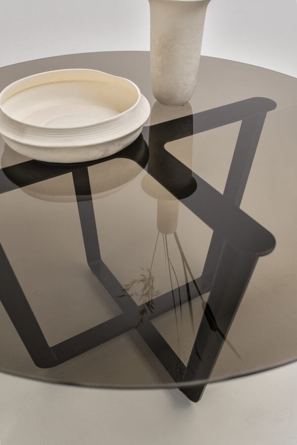 Close-up of the Pietro table showing the reflective glass top and sculptural black base.