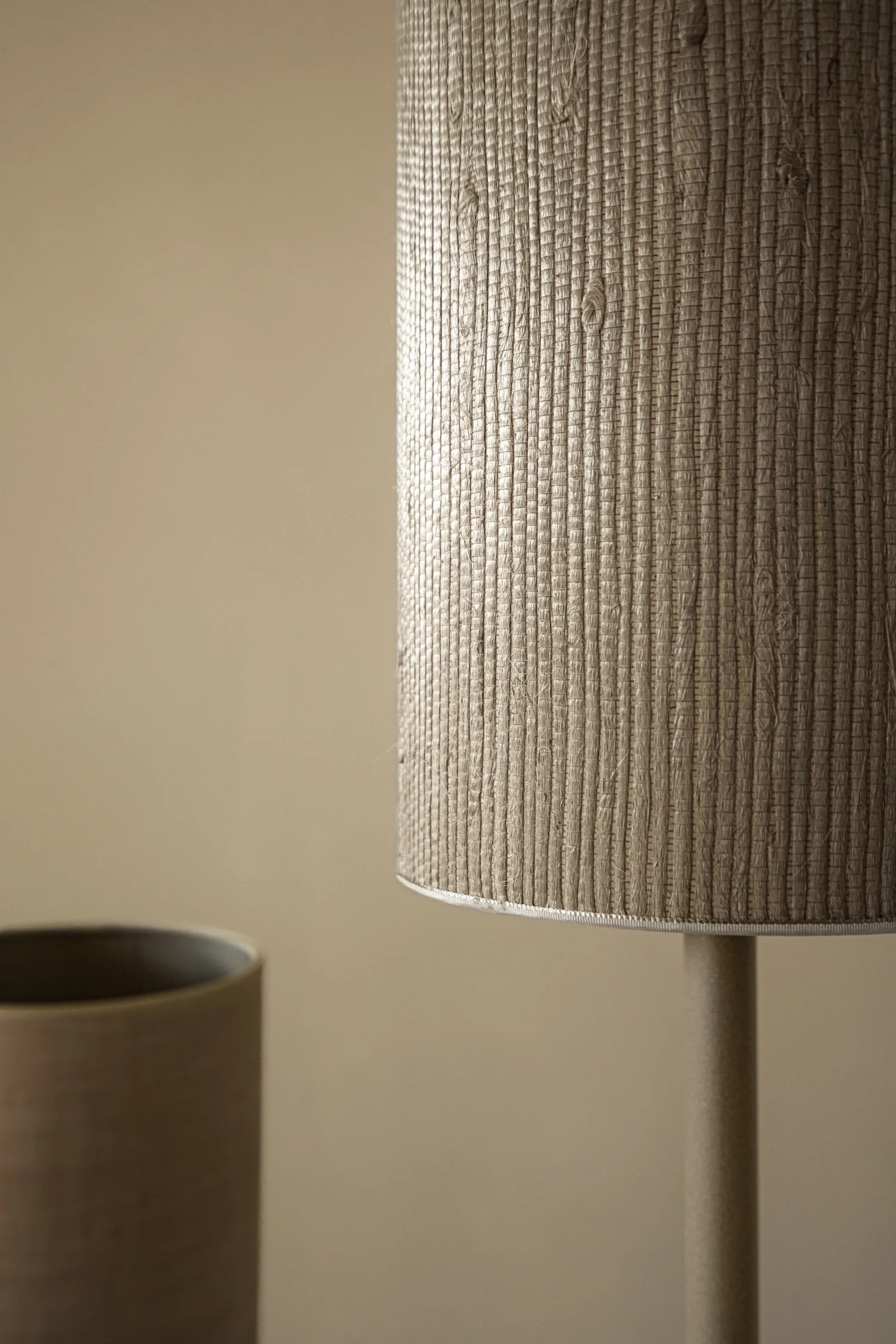 Close-up of a textured cylindrical fabric lampshade in beige tones.