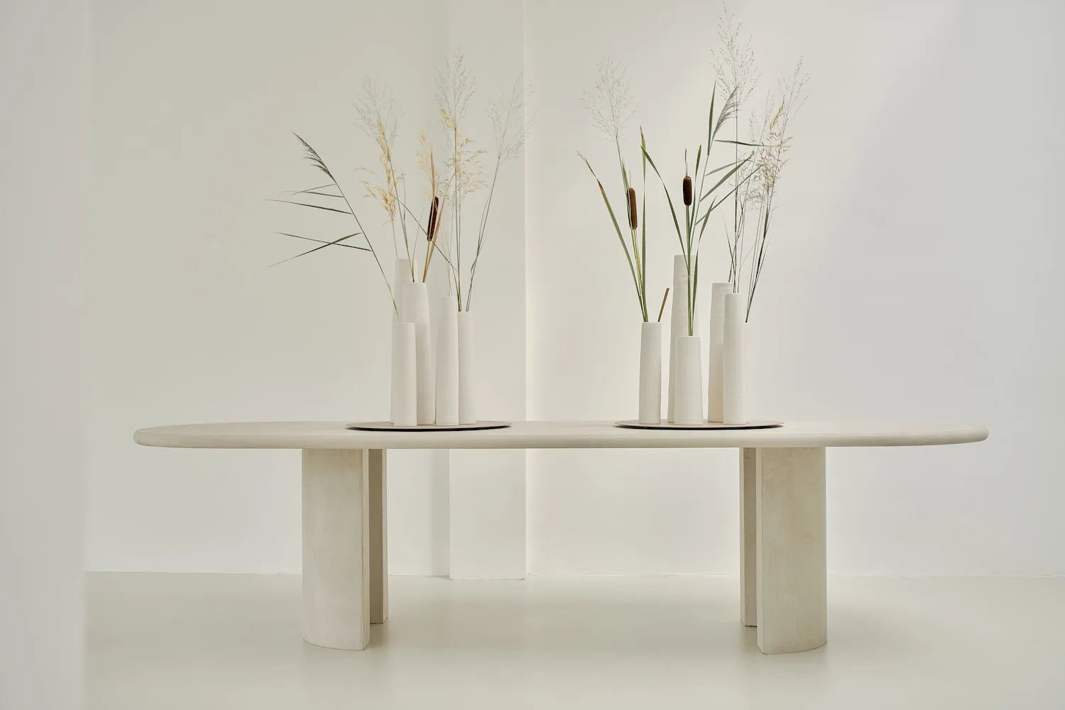 Front view of the Seine dining table styled with two sets of white vases and natural foliage.