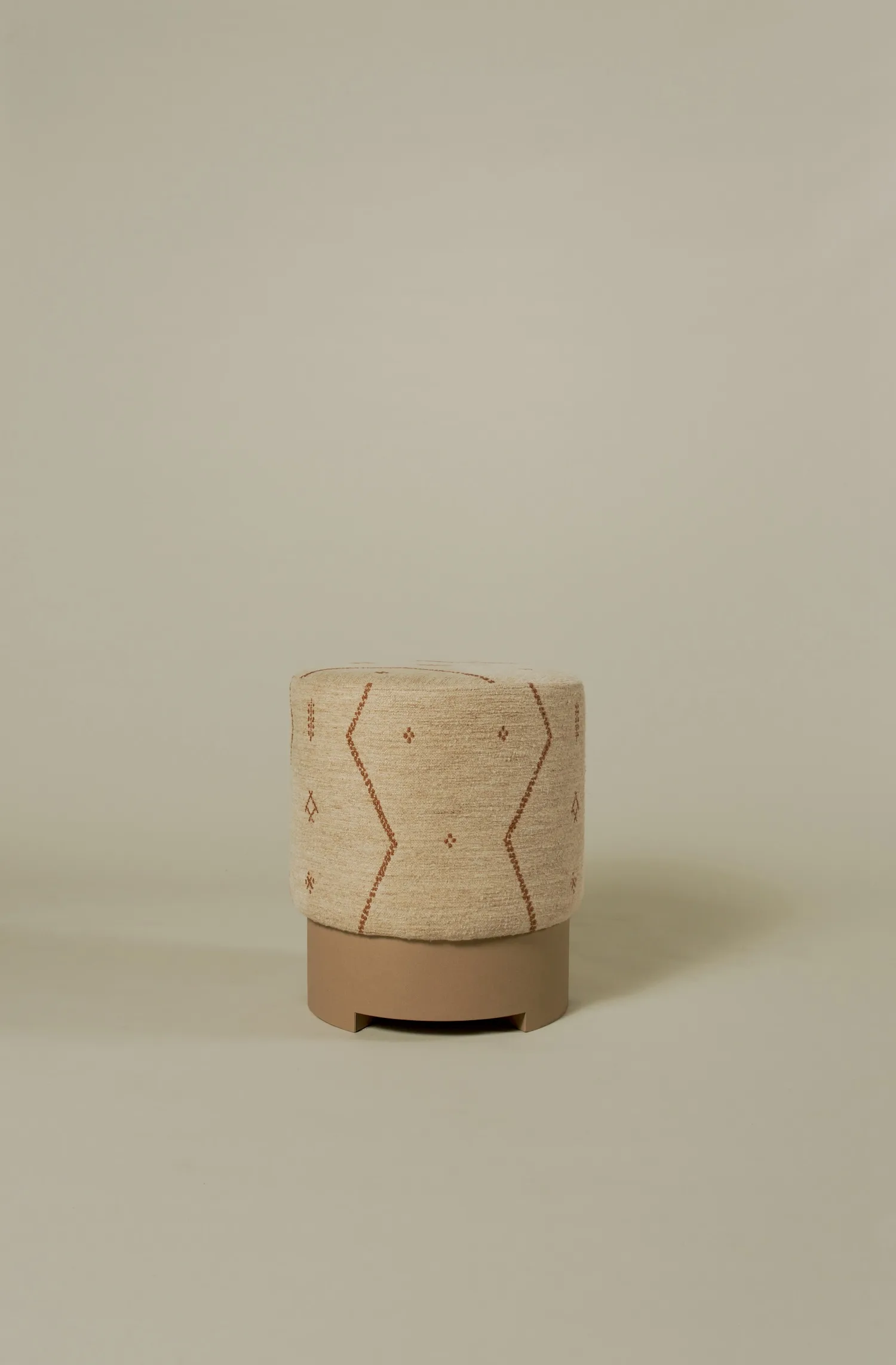Taburetta pouf in beige textile with subtle terracotta geometric pattern and solid base.