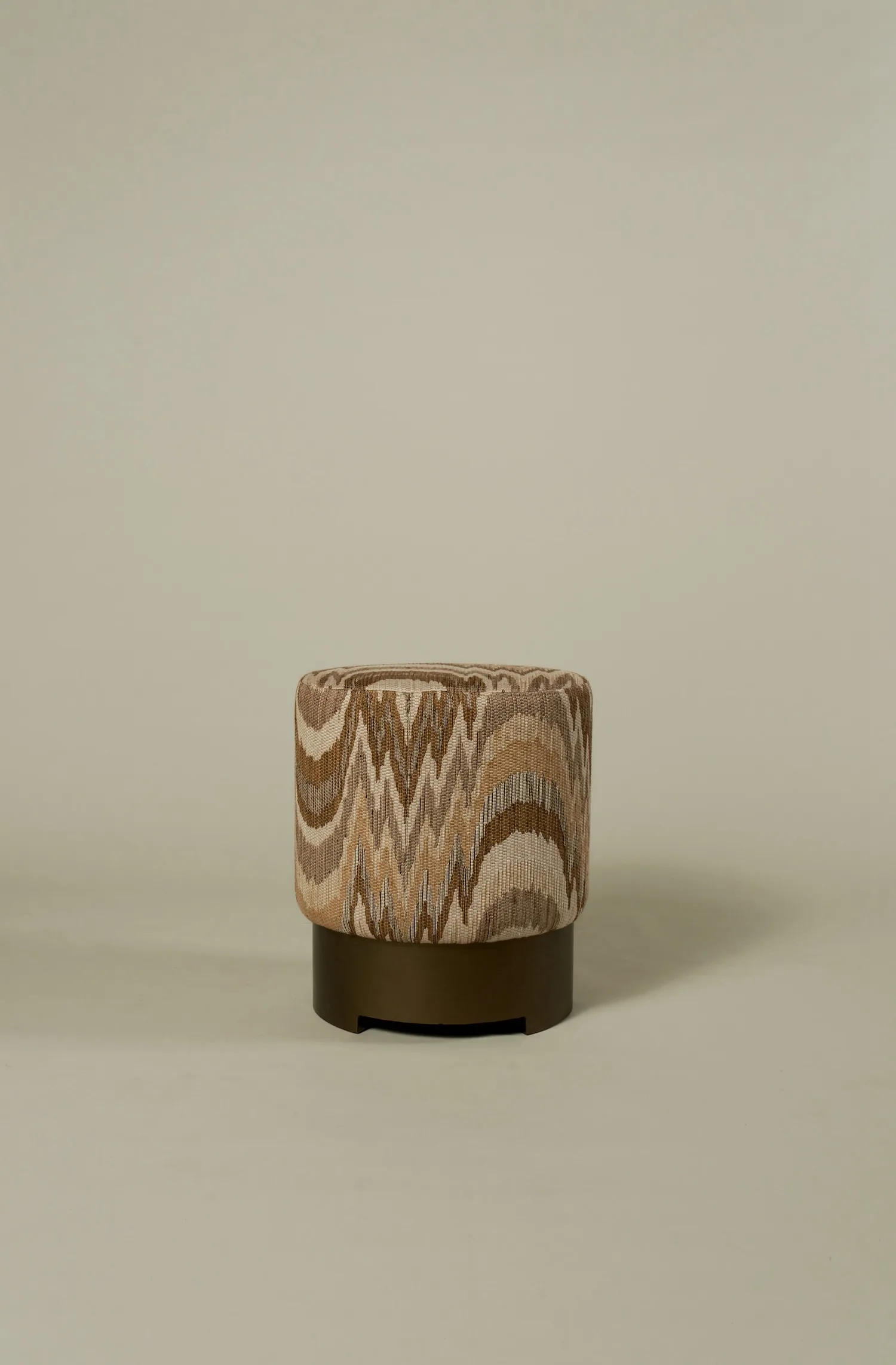Taburetta pouf upholstered in a textured brown and beige patterned fabric.