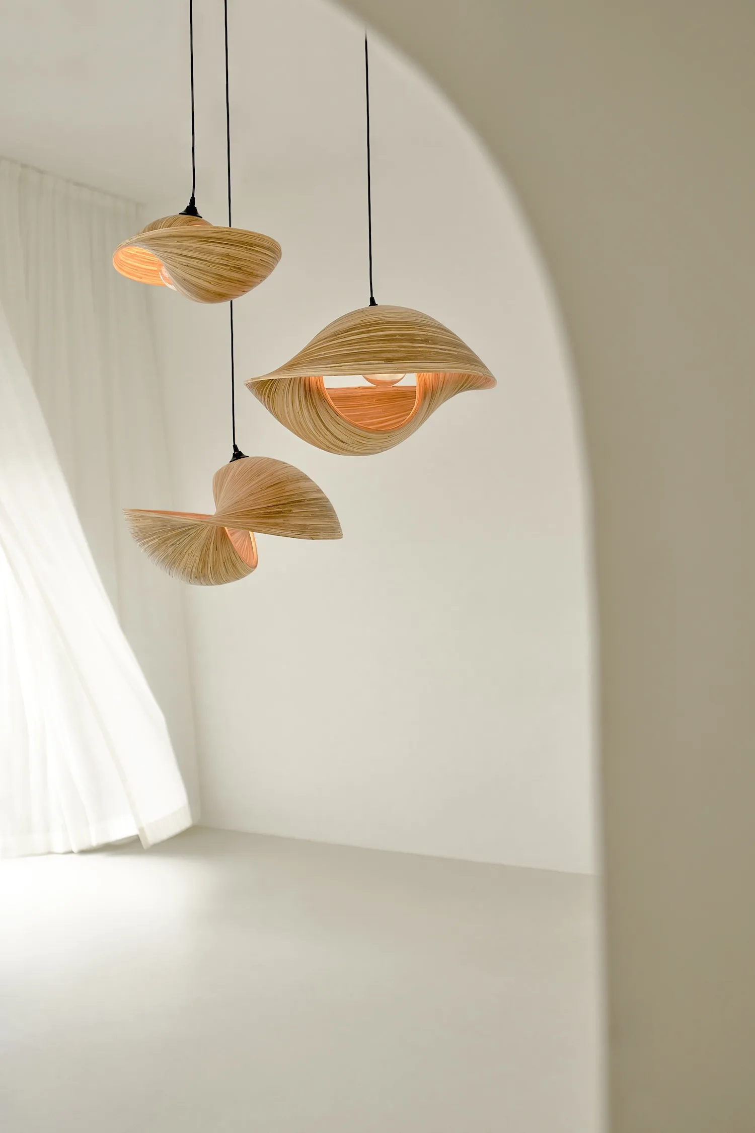 Trio of natural wood Valbonne ceiling lights hanging in a soft-toned, minimal interior space.