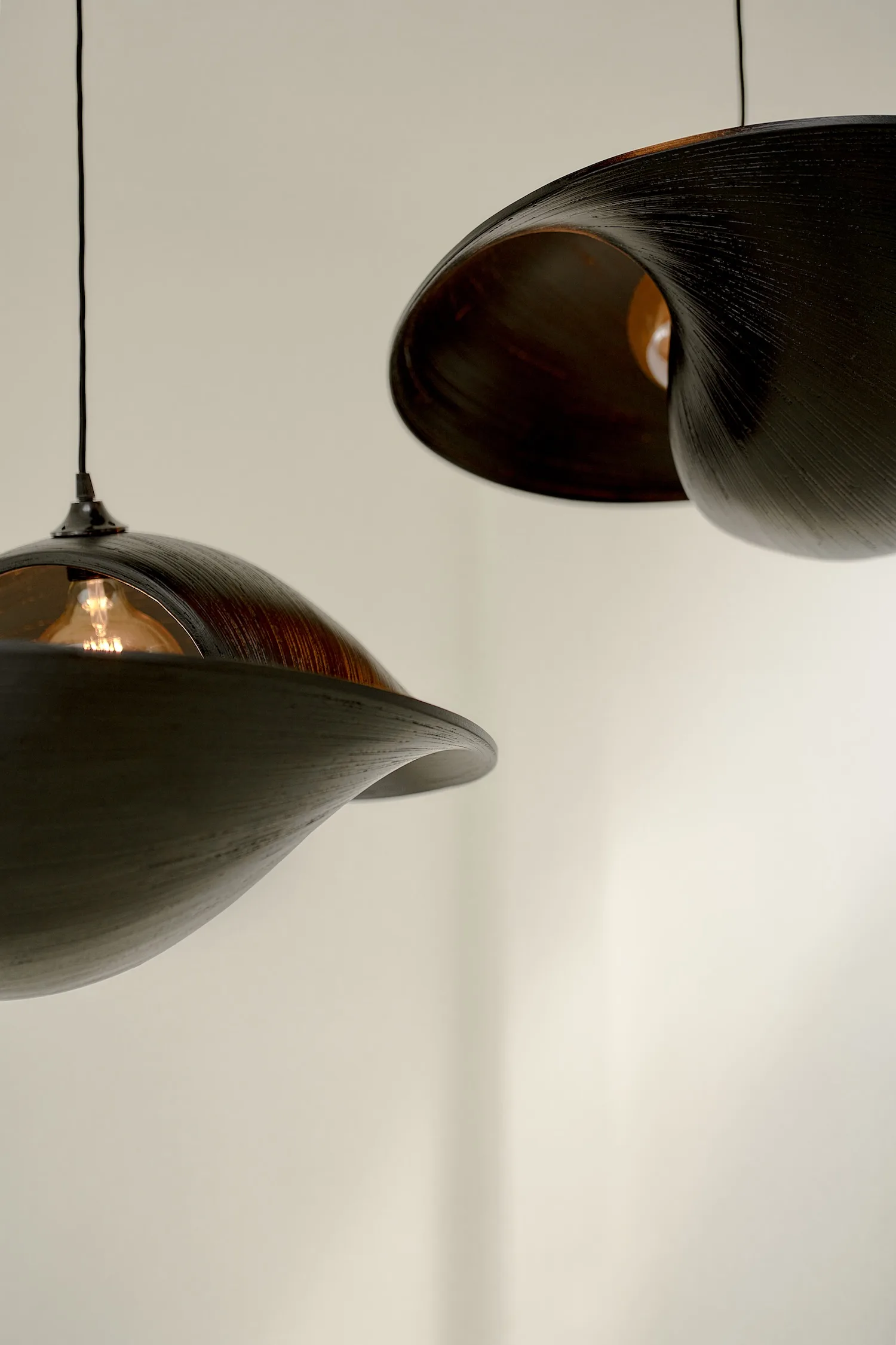 Detailed close-up of the dark Valbonne ceiling light, showing its smooth, curved wooden form.