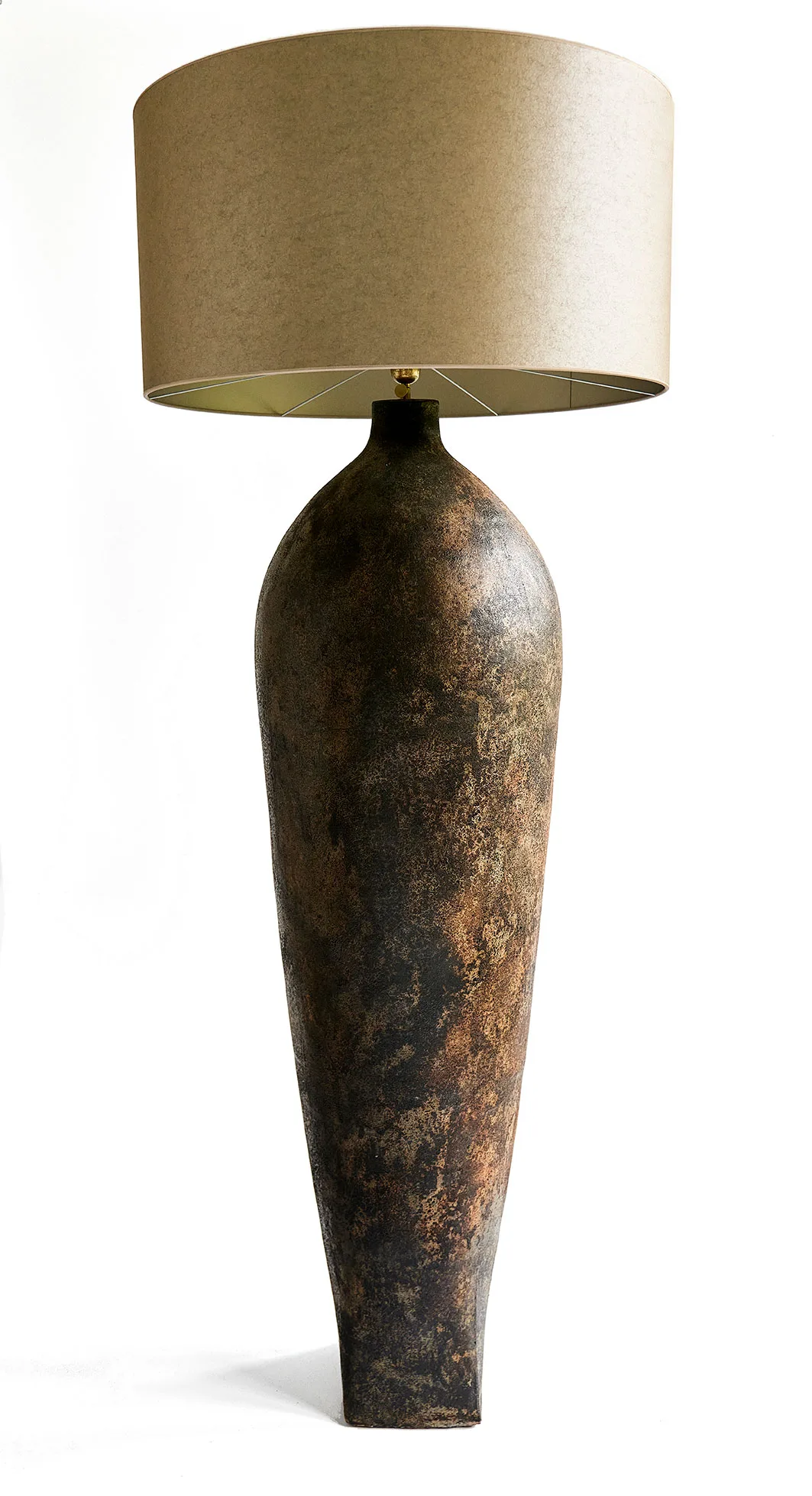 Studio view of the Vorera Vase floor lamp featuring a tall, weathered ceramic base and oversized drum shade.