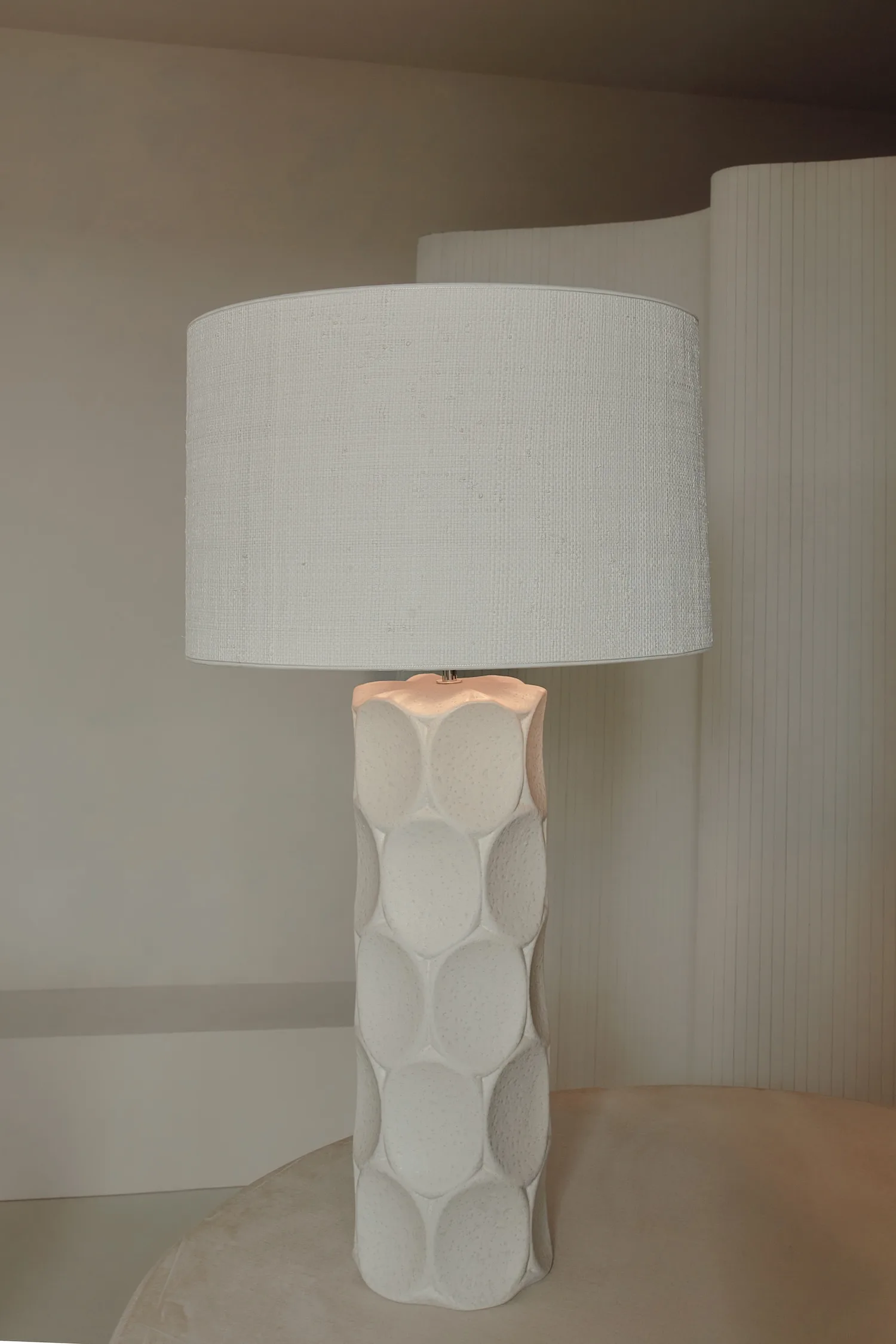 Wabi table lamp featuring a tall base with raised oval textures and a neutral fabric shade.