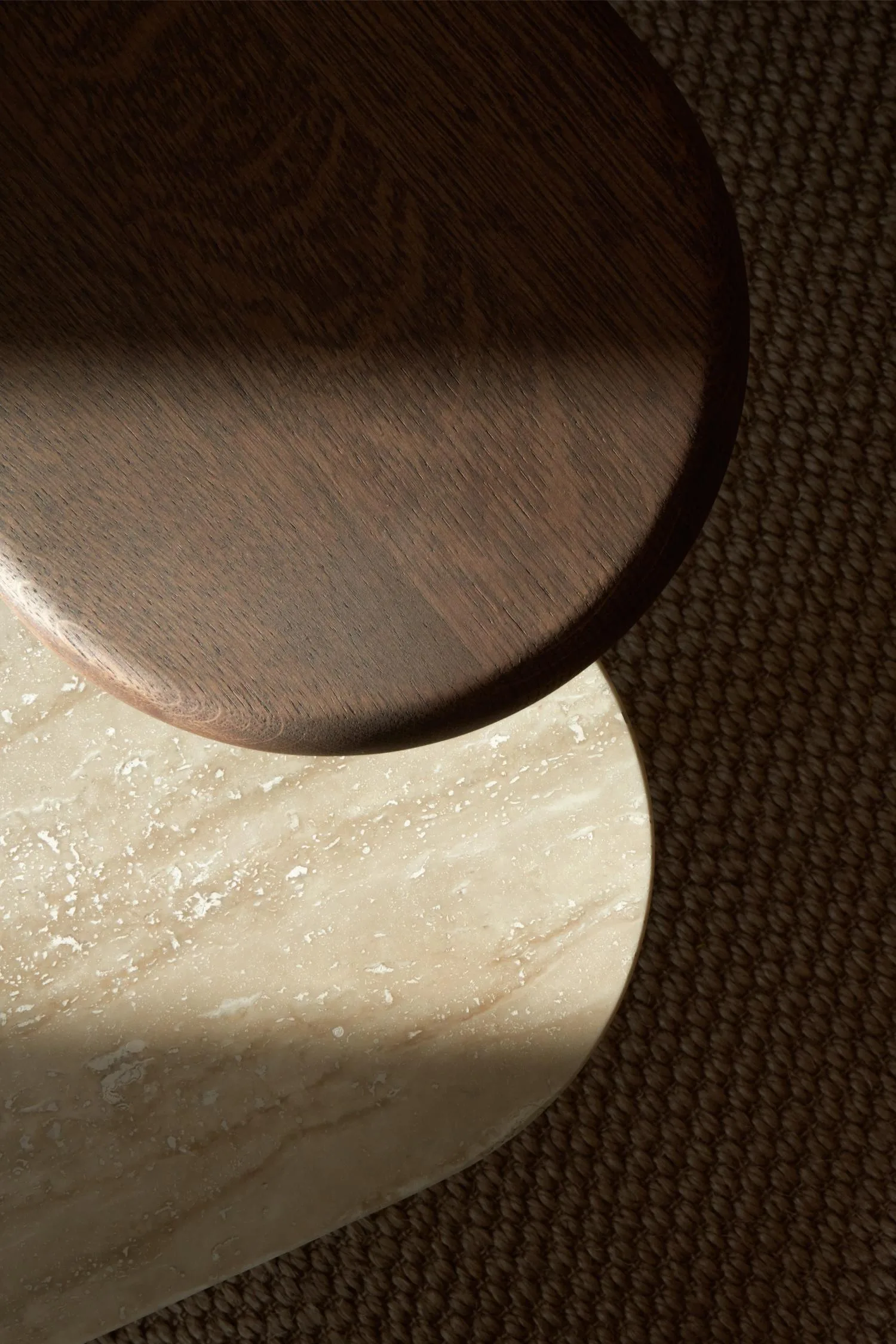 Detailed top view of the Axel Butler table showing the contrast between dark wood and light travertine surfaces.