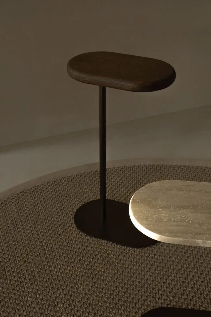 Butler Side table with a dark wood top and a contrasting travertine surface below.