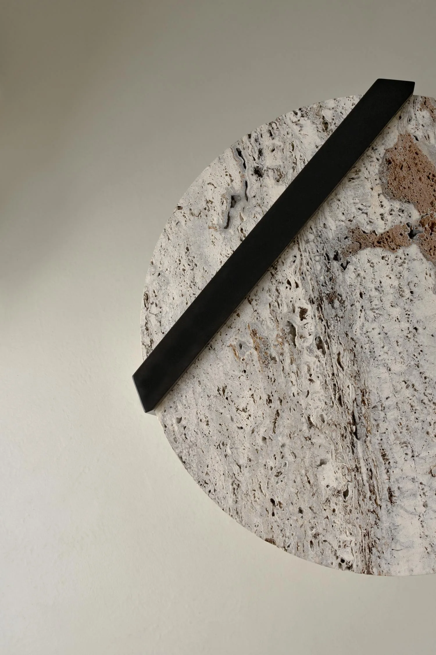 Top view of the Butler side table showcasing the textured travertine surface and black metal handle.
