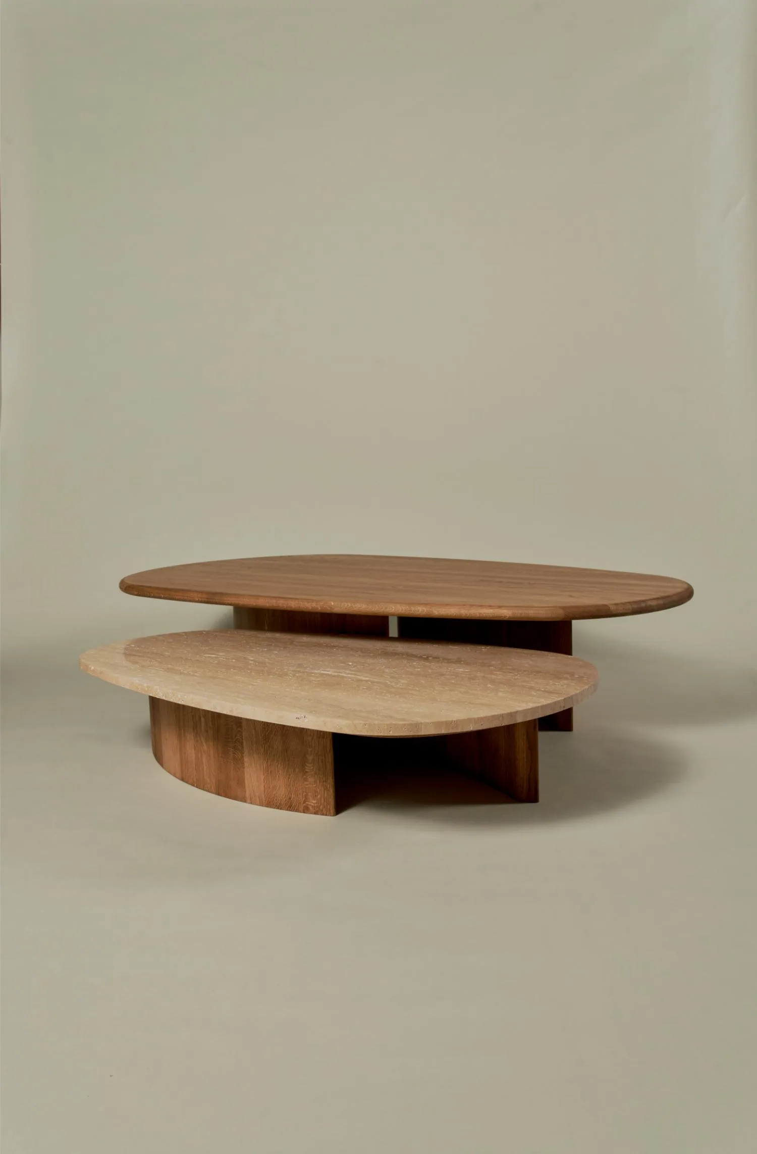 Caprice coffee tables in wood and travertine with rounded shapes.