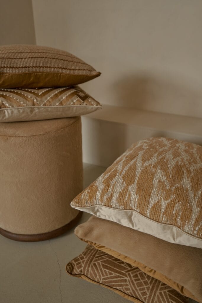 Stack of warm-toned decorative cushions with various woven textures.