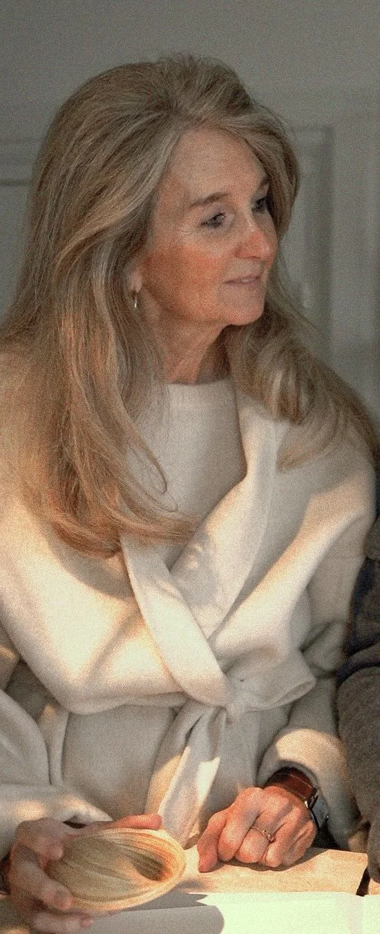 Ellen holding a wooden object while seated at a table.