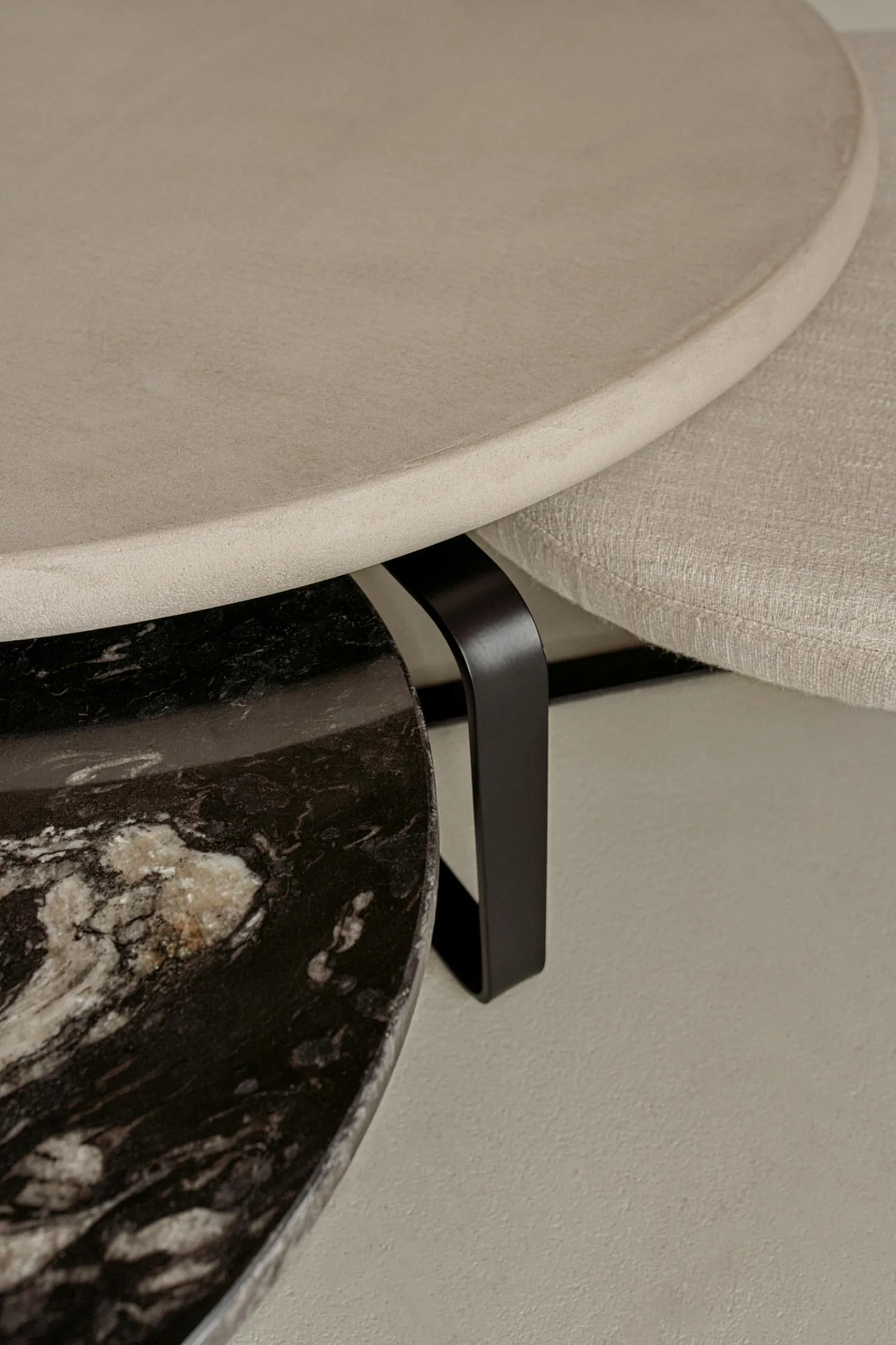 Detailed view of Lora coffee table surfaces showing the texture contrast between soft fabric, smooth beige stone, and polished black marble.