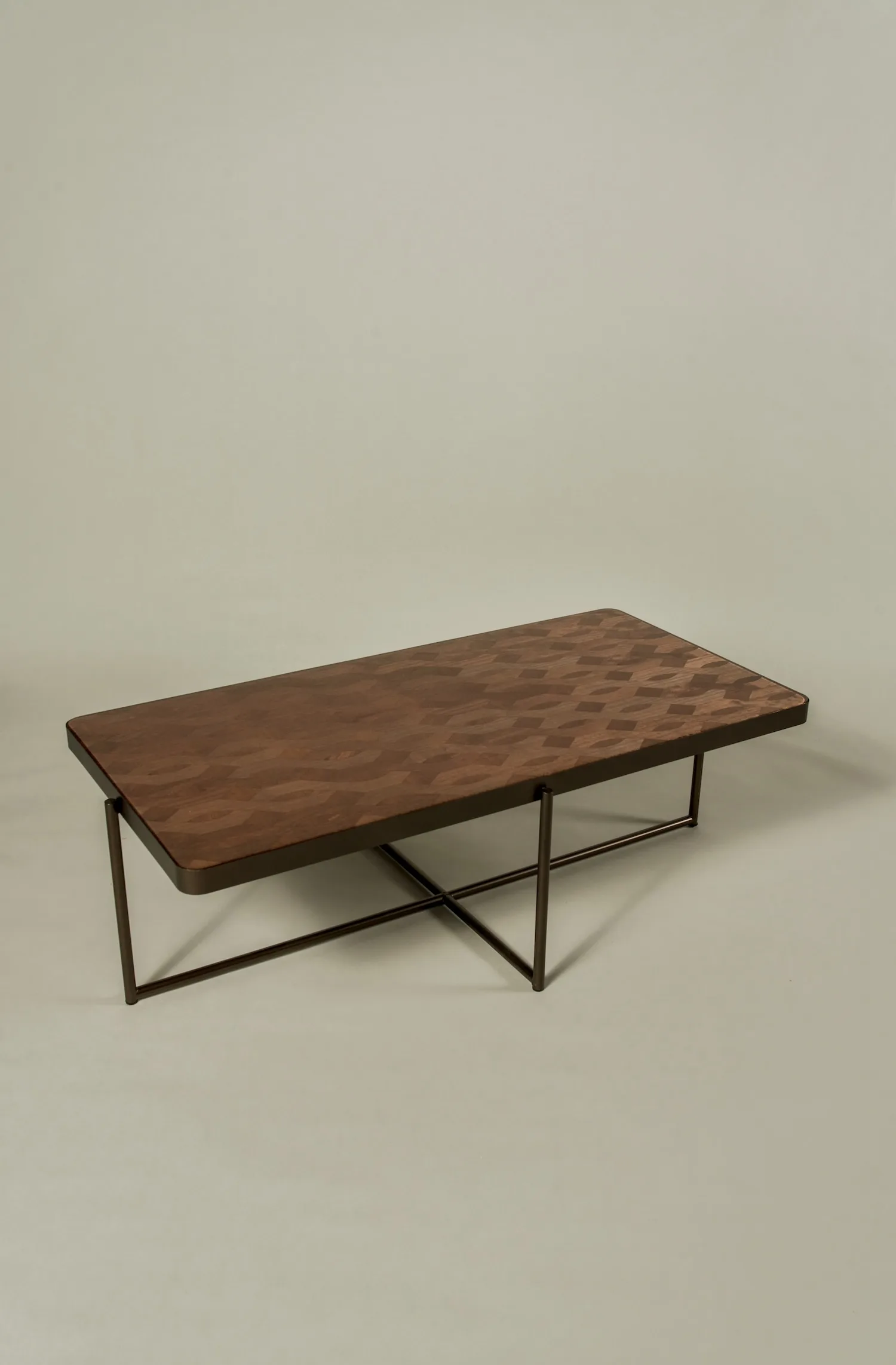 Lucca coffee table with geometric inlay wood top and slim metal frame, shown in a minimalist studio setting.