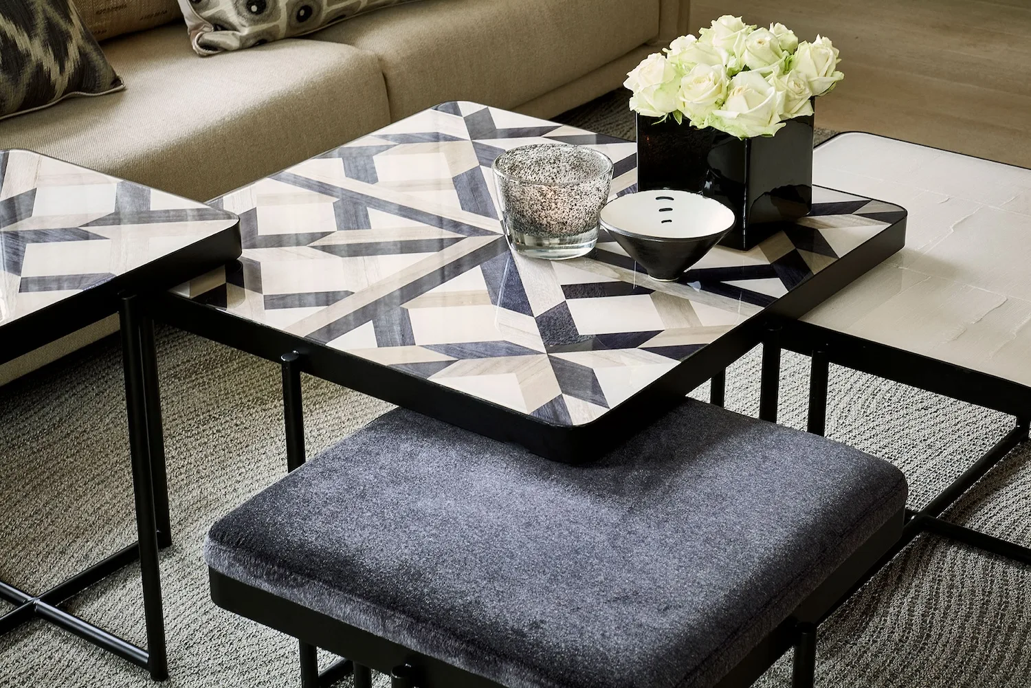 Lucca coffee table with bold geometric inlay pattern, styled with decor items like a black vase, white bowl, and flowers.